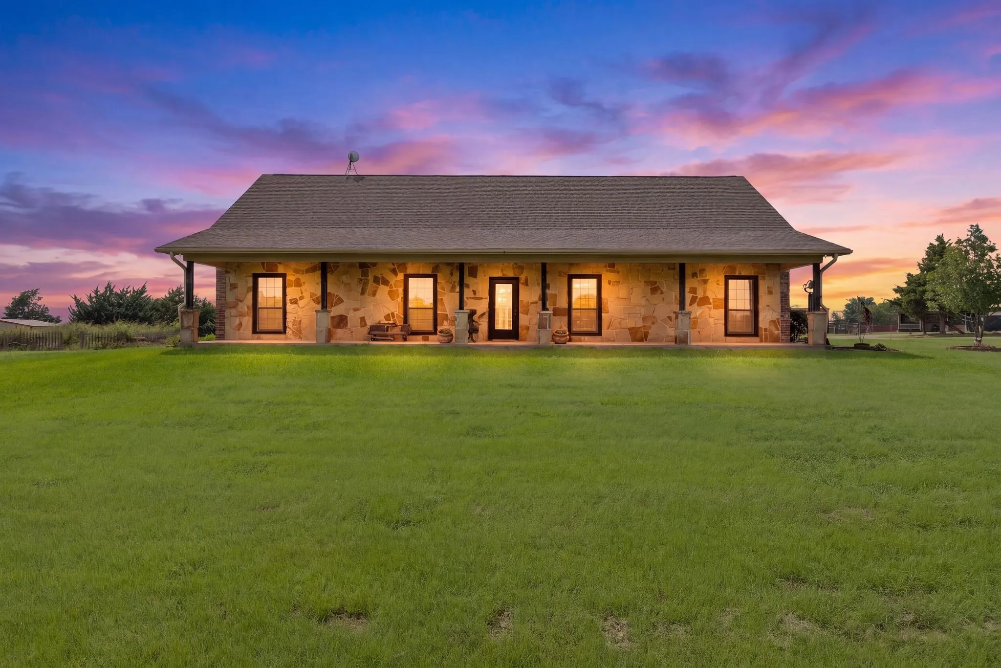 Stone facade residence with a broad front porch, multiple windows, and a classic gabled roof