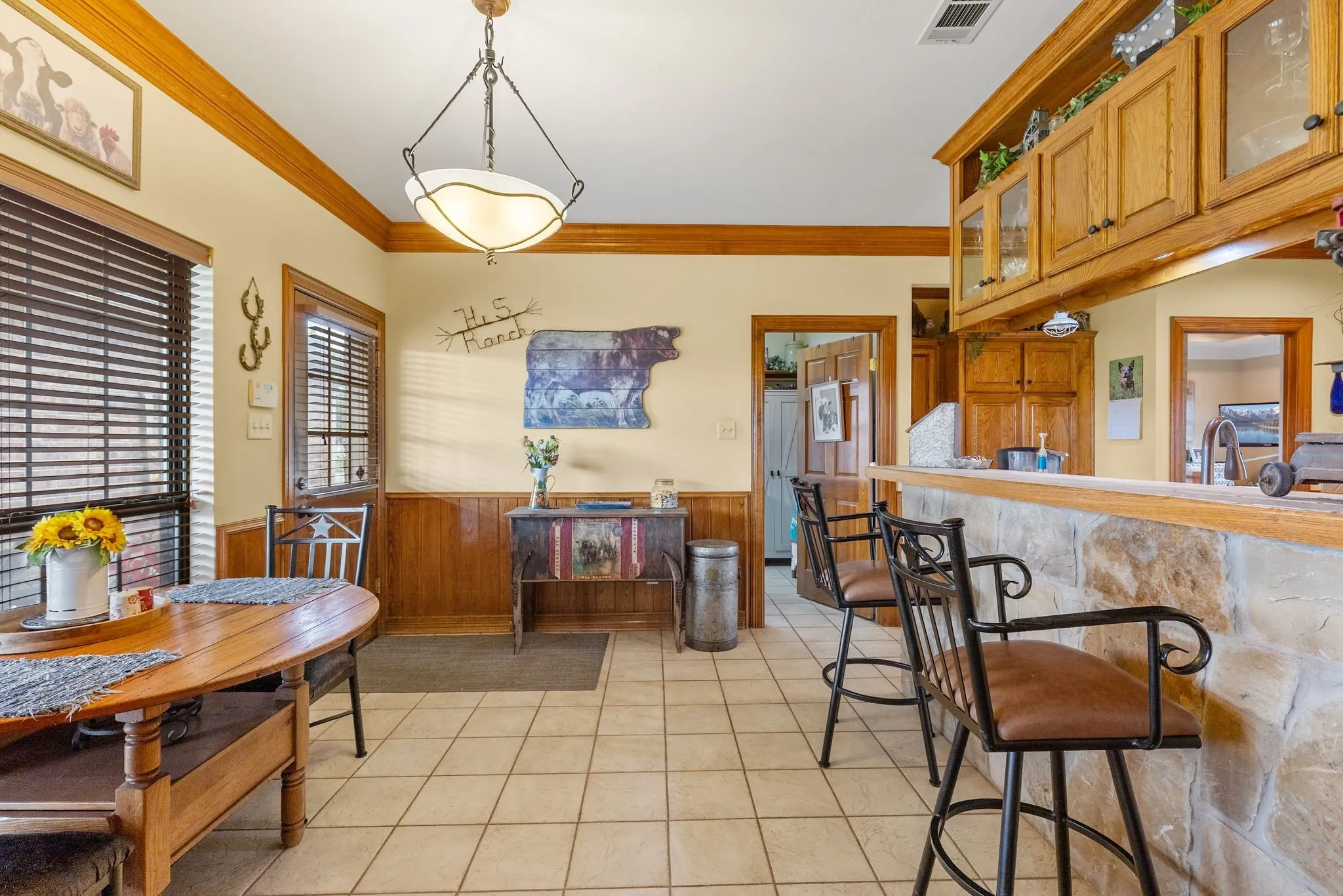 Open concept kitchen area featuring tile flooring, wood paneling, and an exposed stone breakfast bar with seating