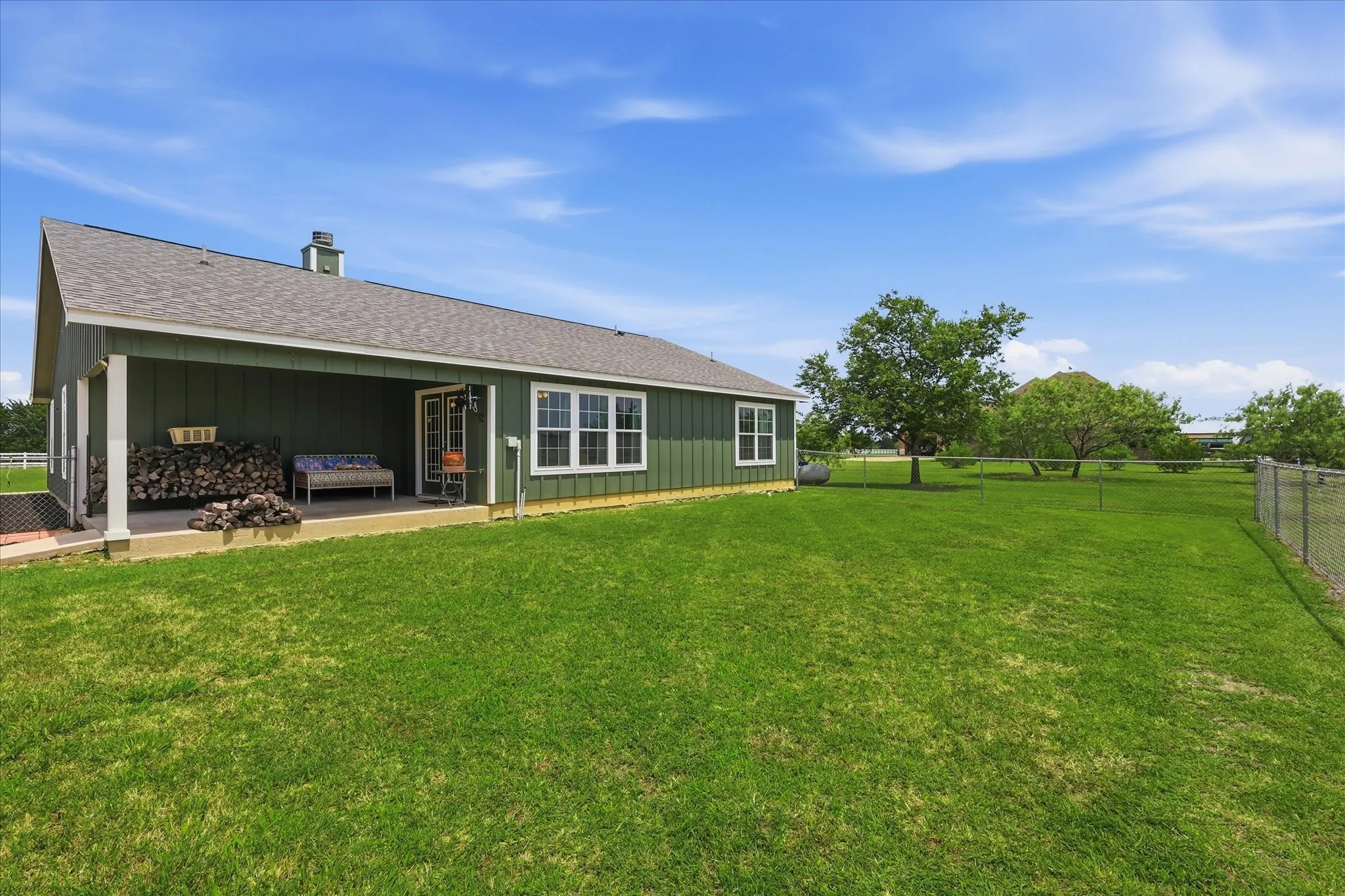 Expansive green lawn surrounds a single-story structure with a covered patio
