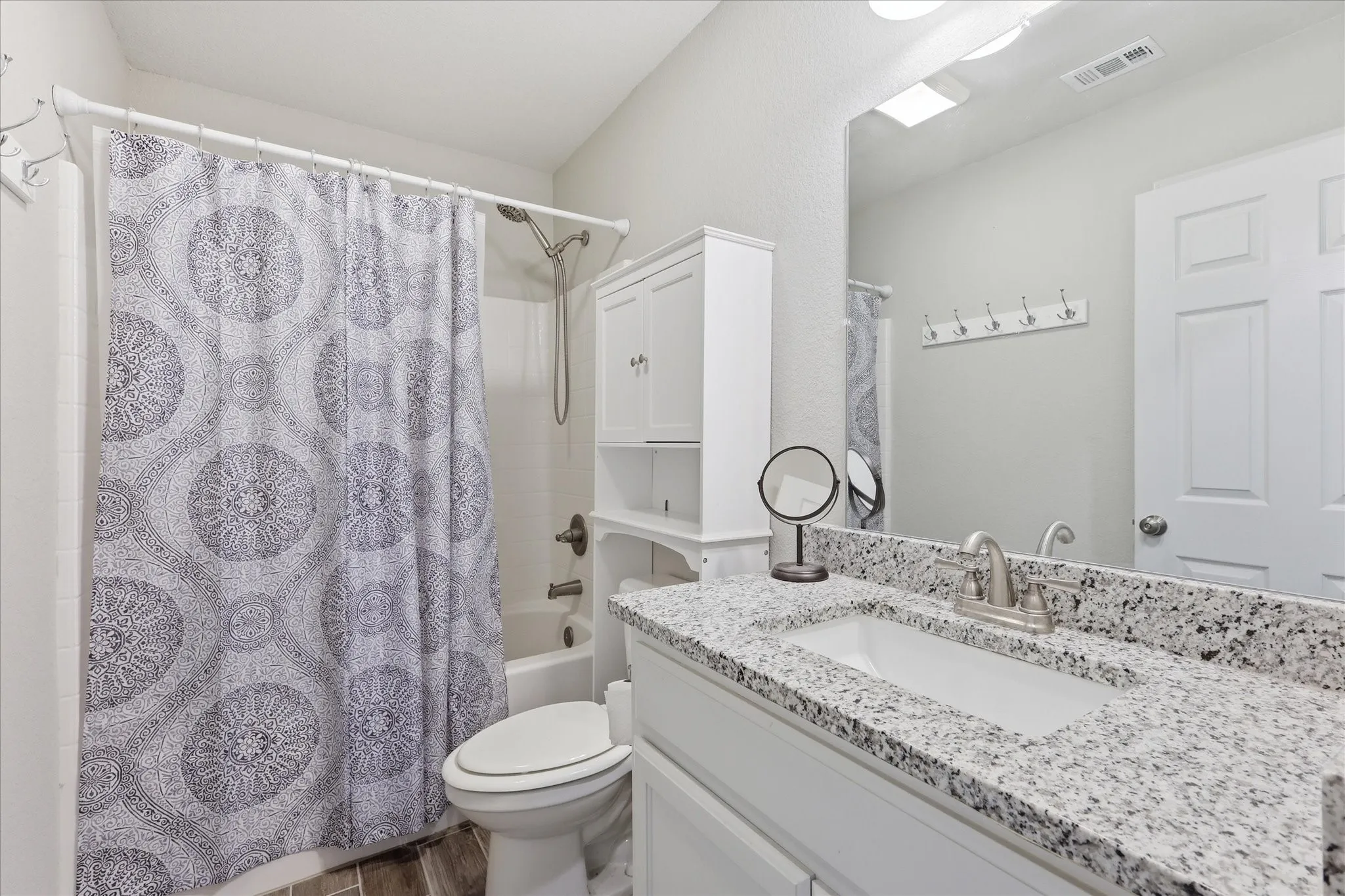 Bathroom vanity with a speckled countertop, undermount sink, and brushed nickel faucet
