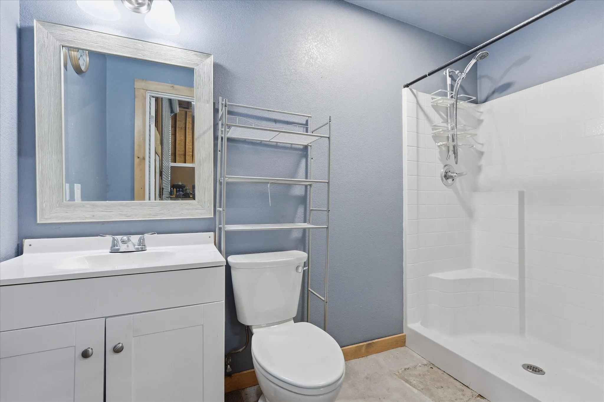 Shop Bathroom featuring a white vanity with integrated sink, framed mirror, and a walk-in shower with white subway tile-patterned walls and a corner seat