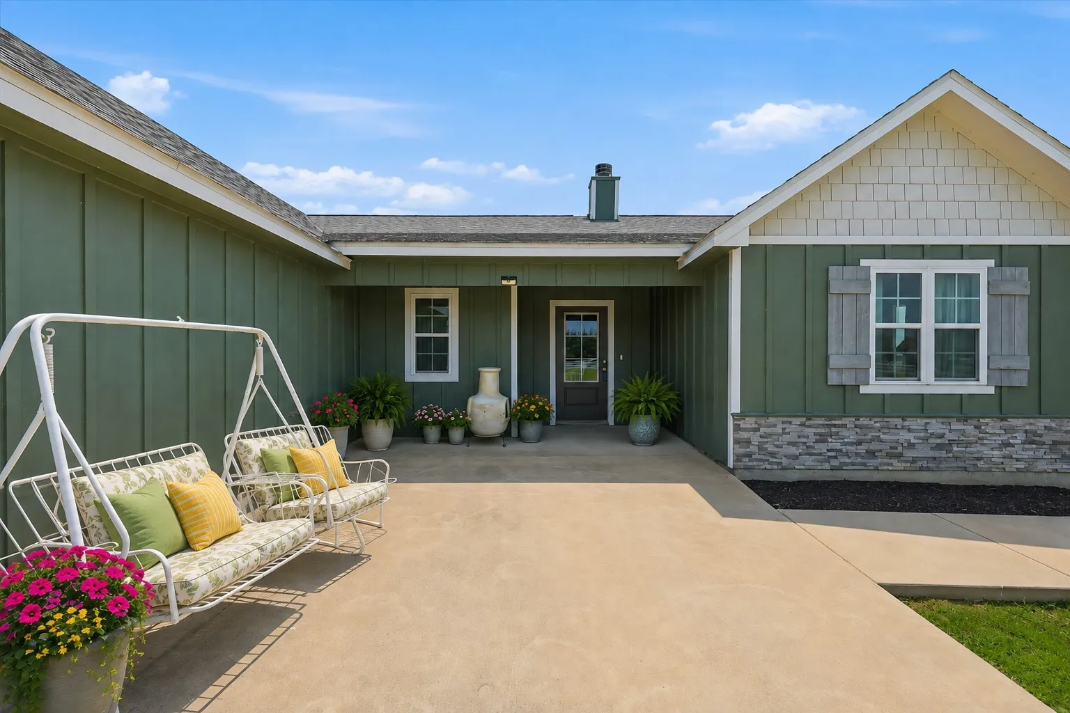 Virtually Staged Board and batten siding with stone accents, a covered entry, an exterior lighting fixture, and a glass-paneled entry door