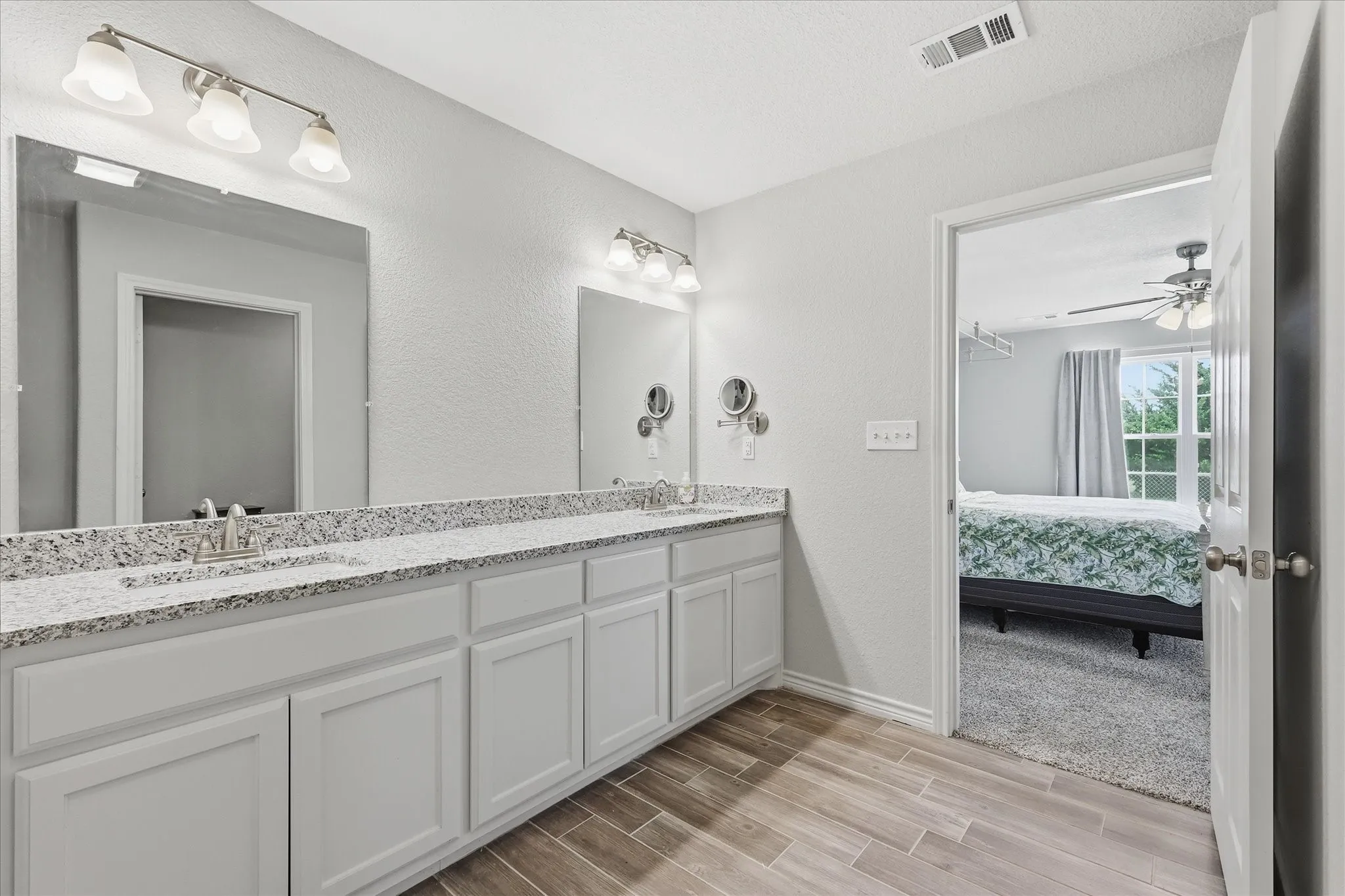 Dual vanity with white cabinetry, granite-finish countertops, and chrome fixtures