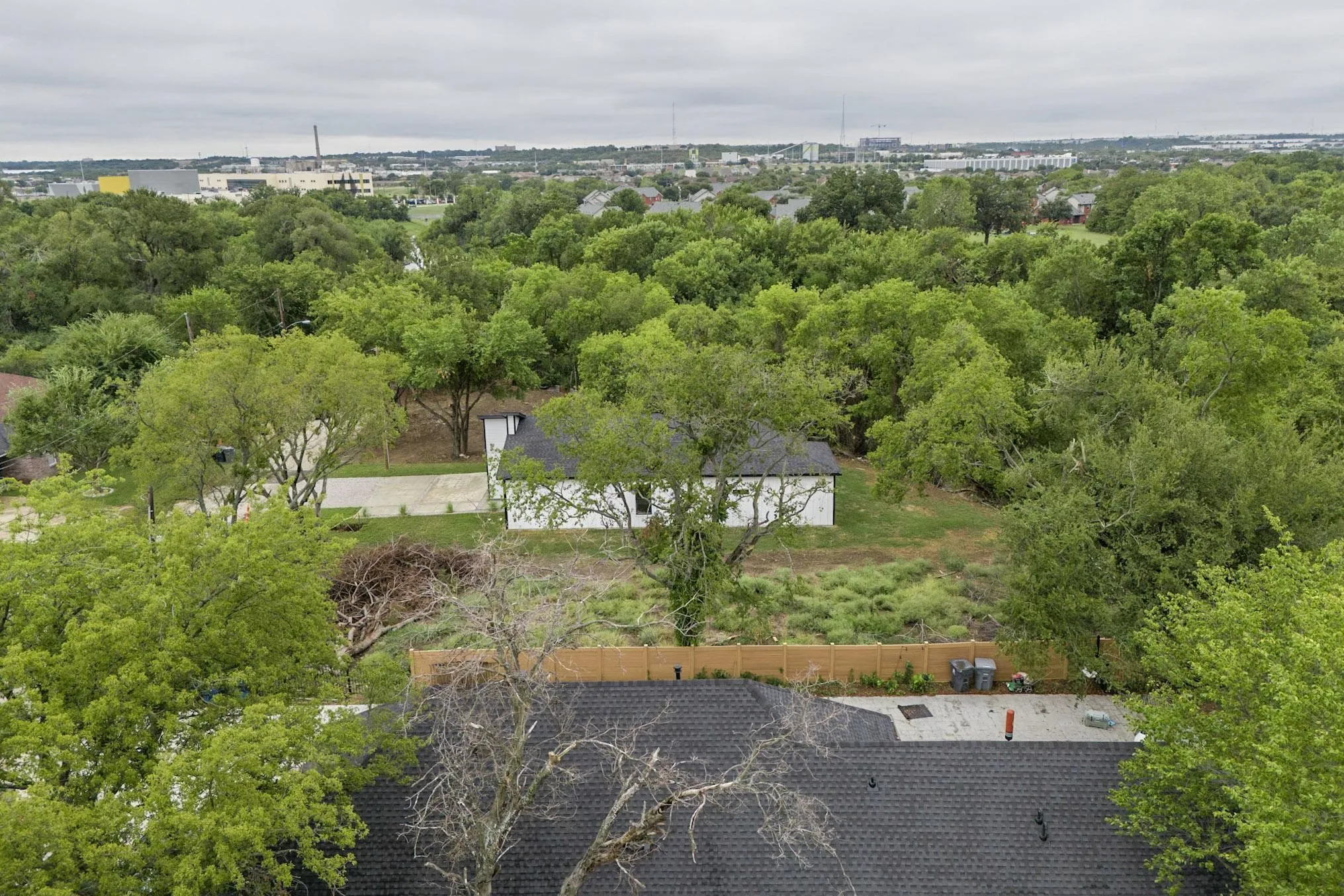 Aerial perspective showcasing a single-story residence with a white exterior, a dark roof, and a visible driveway