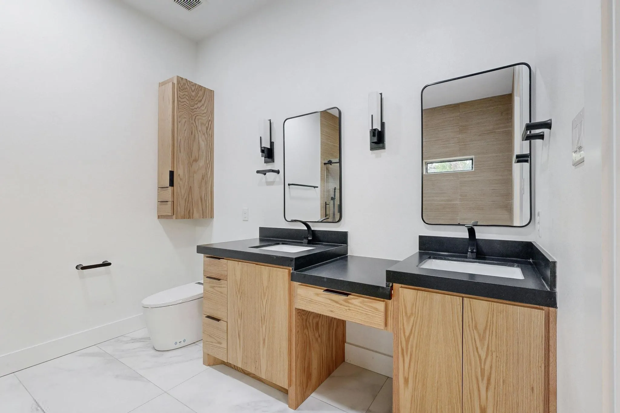 Dual vanity with wood-finish cabinetry, dark countertops, and undermount sinks