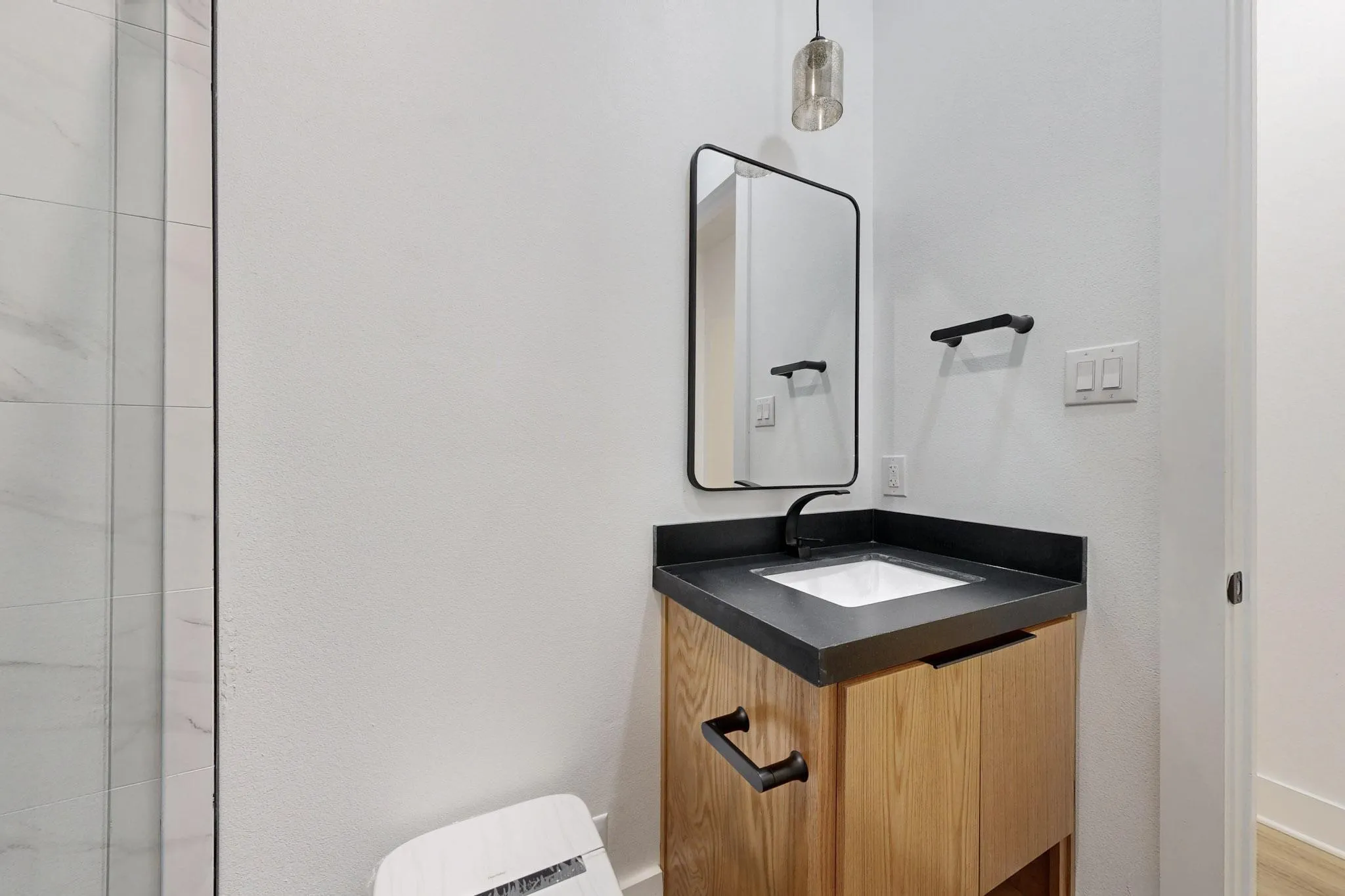 Modern bathroom vanity with a dark countertop, undermount sink, and matte black fixtures