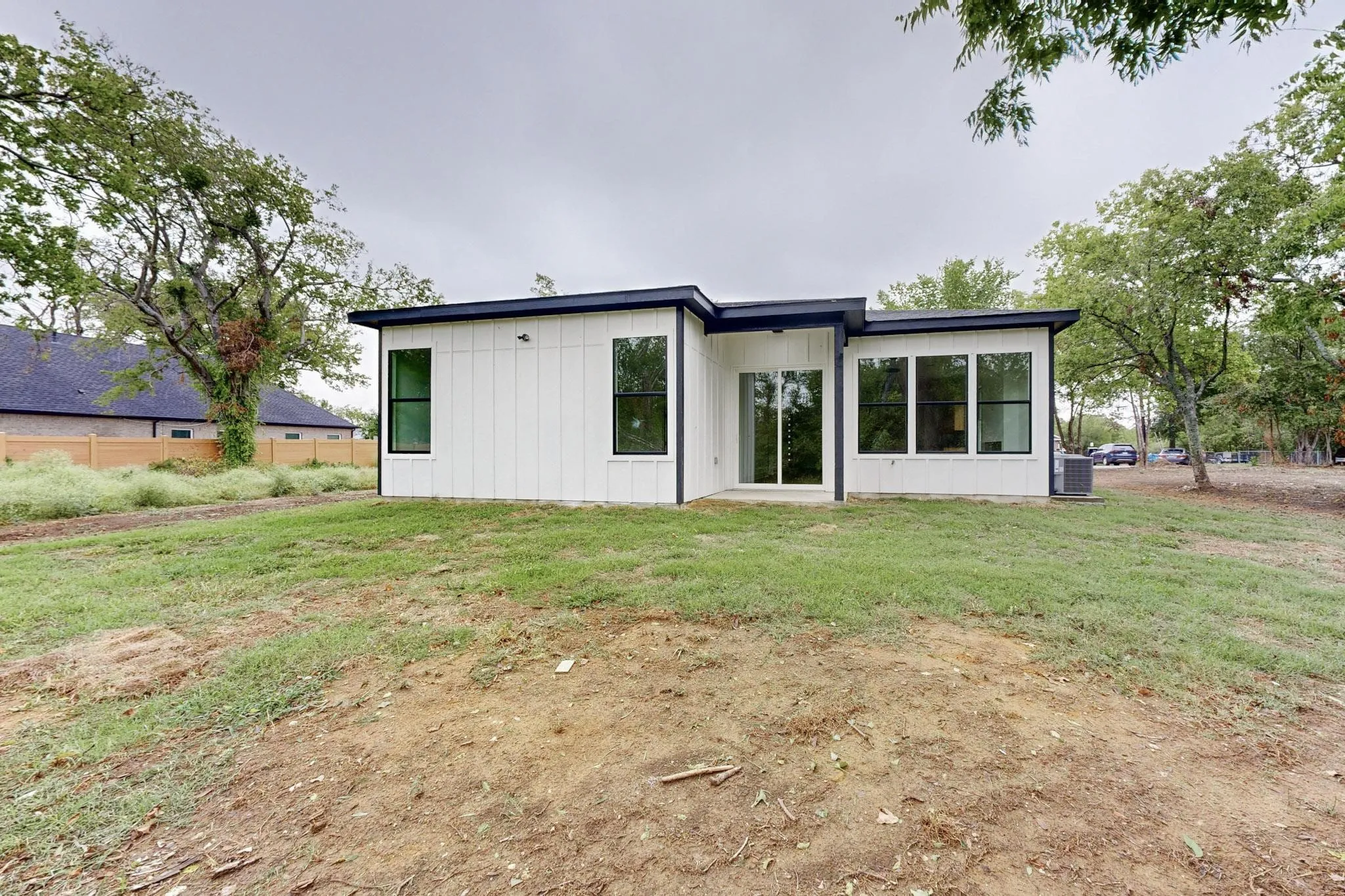 Modern white facade with black trim, featuring a flat roofline, multiple large windows, and a glass sliding door