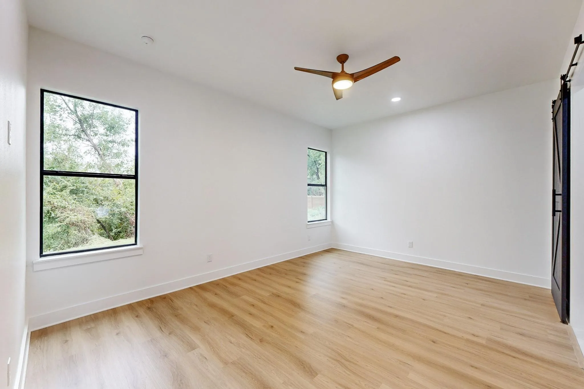 Bright interior room featuring wood-finish flooring, recessed lighting, and a contemporary ceiling fan