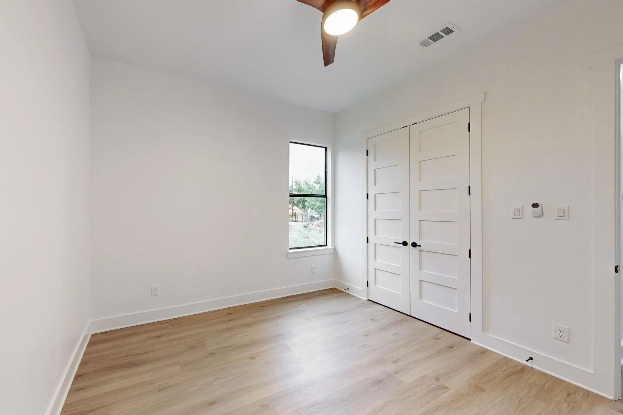 Room featuring wood-finish flooring, white baseboards, and bright white walls