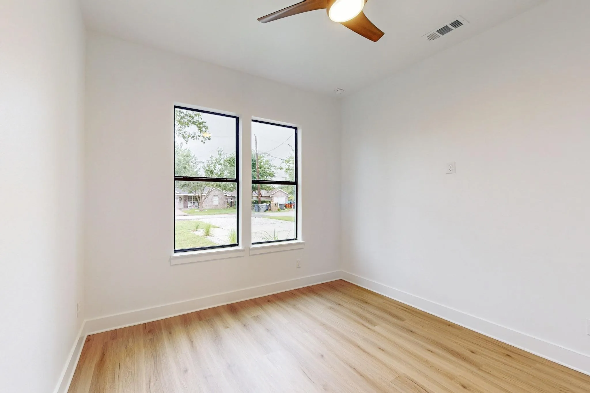 Bright interior space featuring wood-finish flooring, white walls, and a ceiling fan