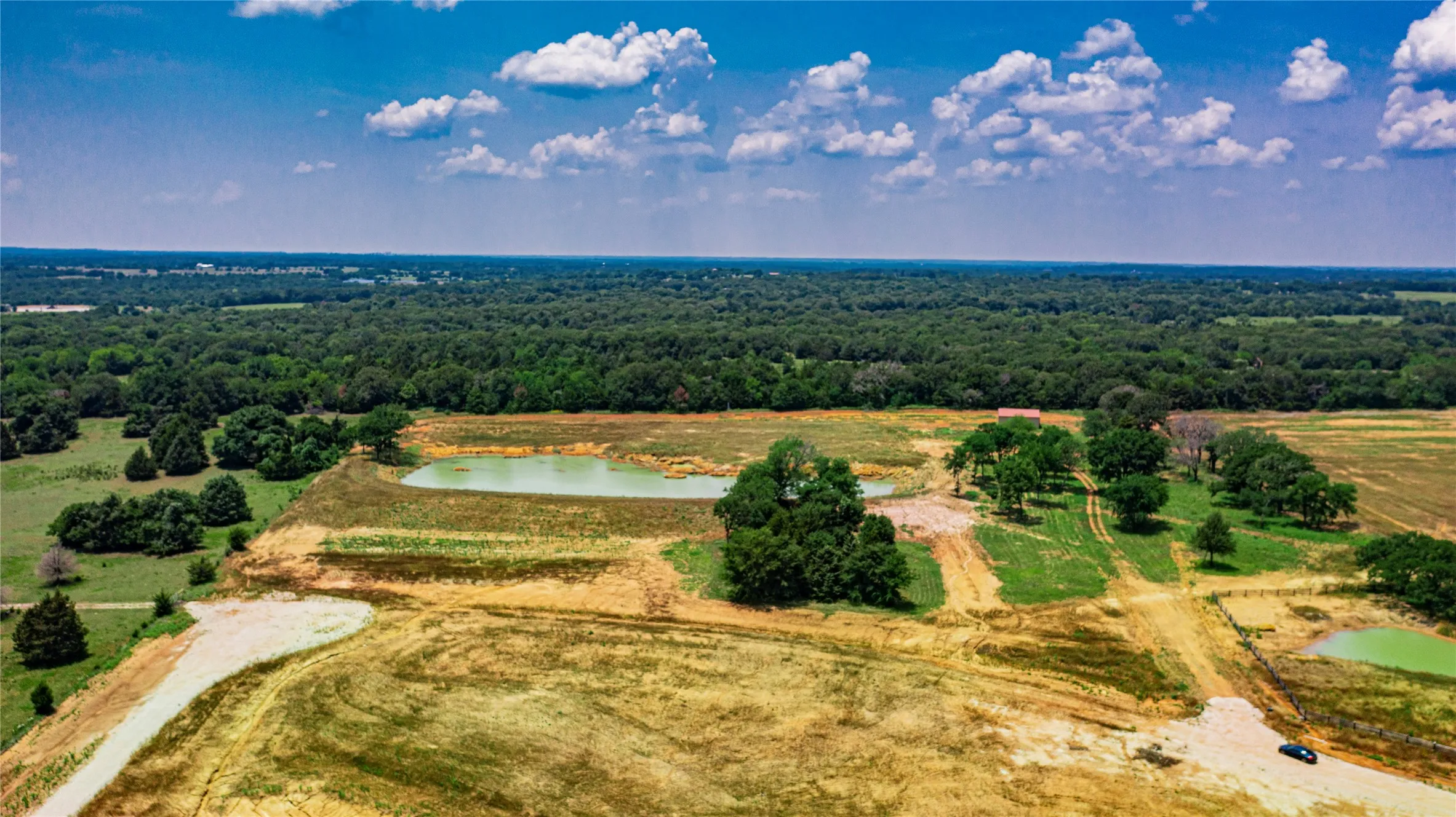 Expansive rural land featuring two ponds, established trees, and surrounding wooded areas