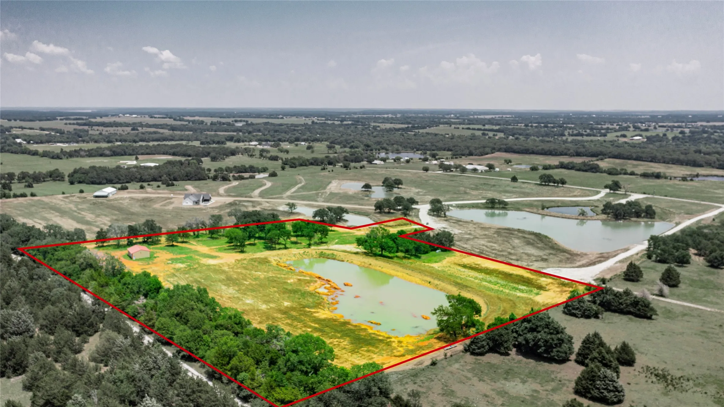 Expansive acreage featuring a private pond, open fields, and established tree lines