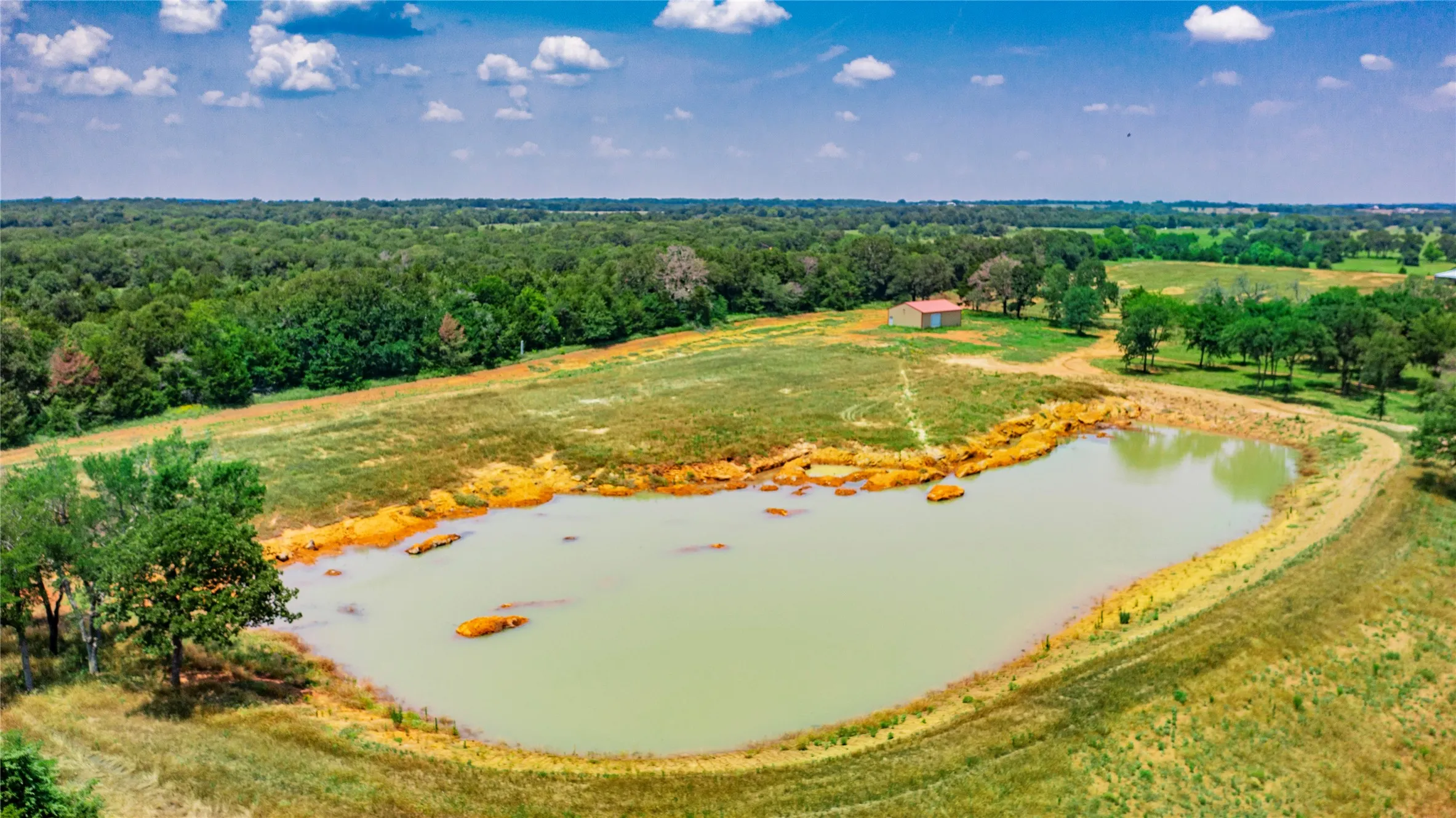 Expansive property featuring a large pond with a naturalized shoreline