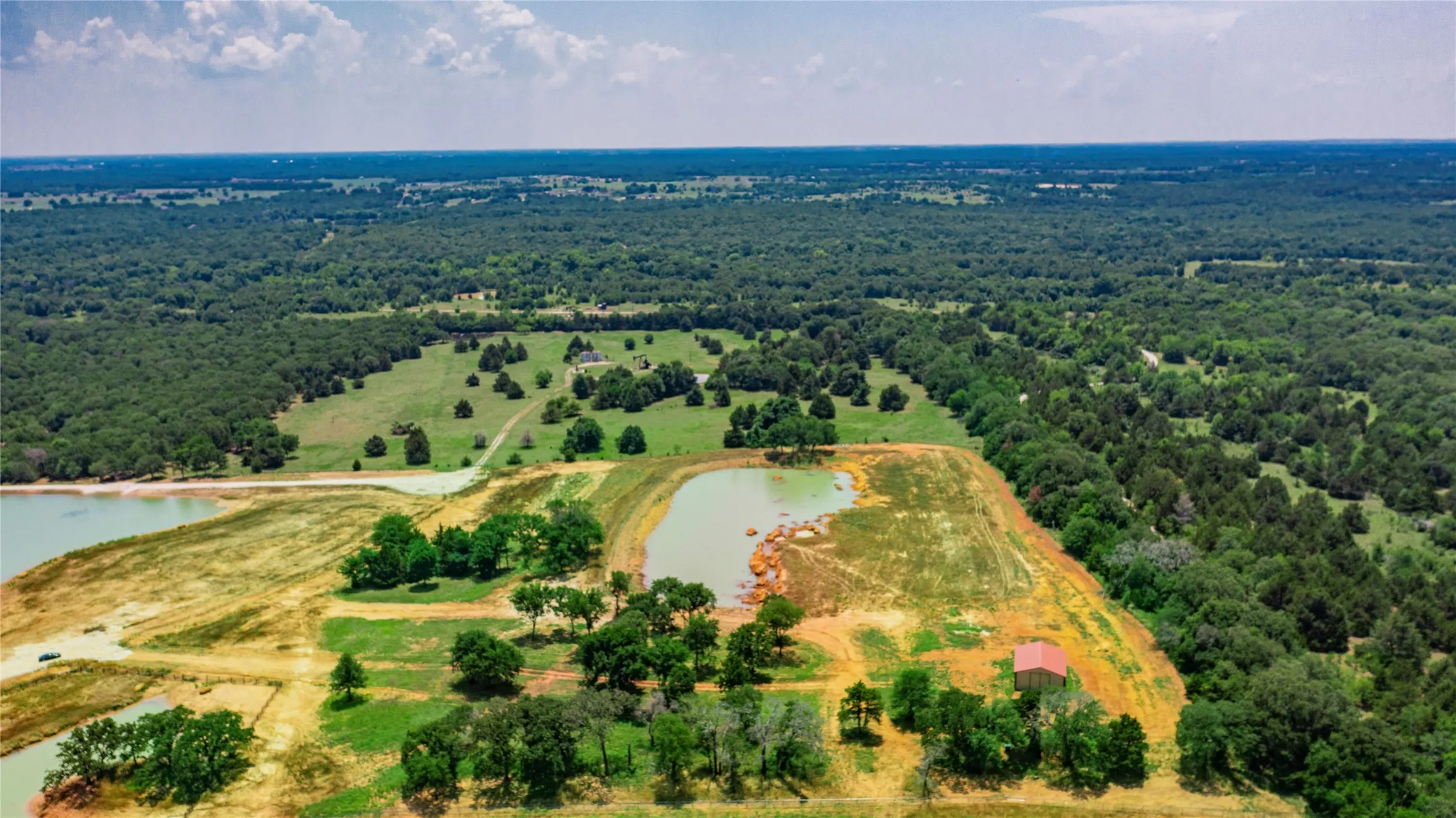 Expansive property featuring multiple ponds, wooded areas, and open clearings