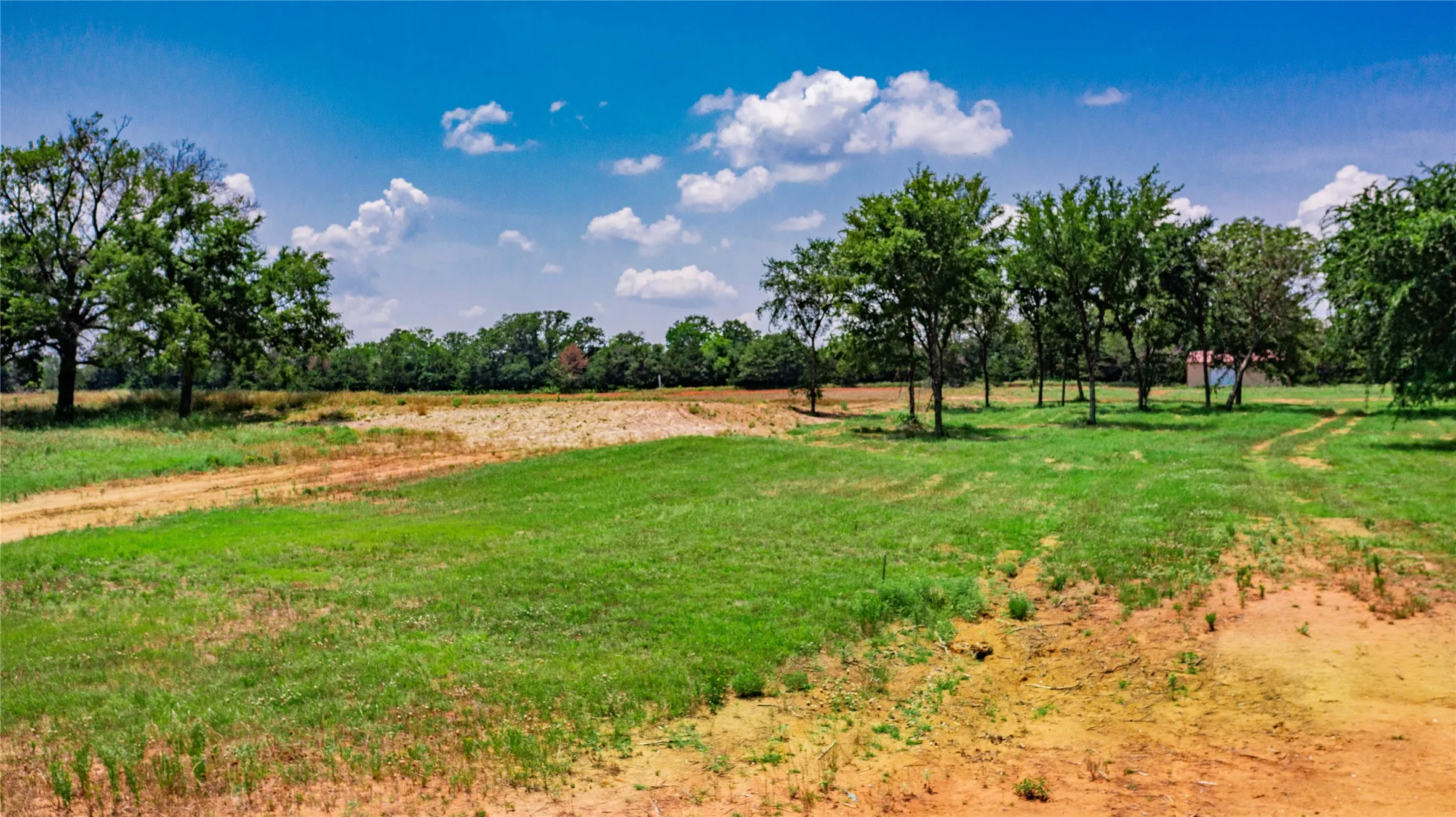Expansive lot featuring varied terrain with sections of green grass and areas of exposed earth