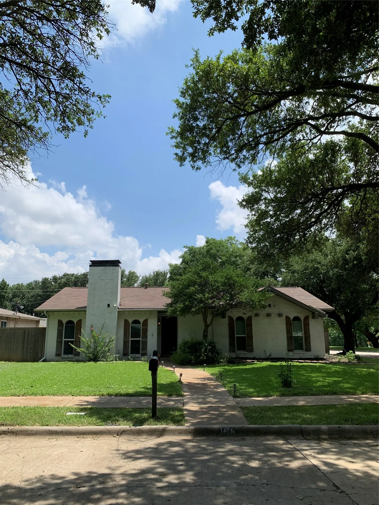 Single-story residence featuring a prominent white brick chimney and arched windows with dark shutters