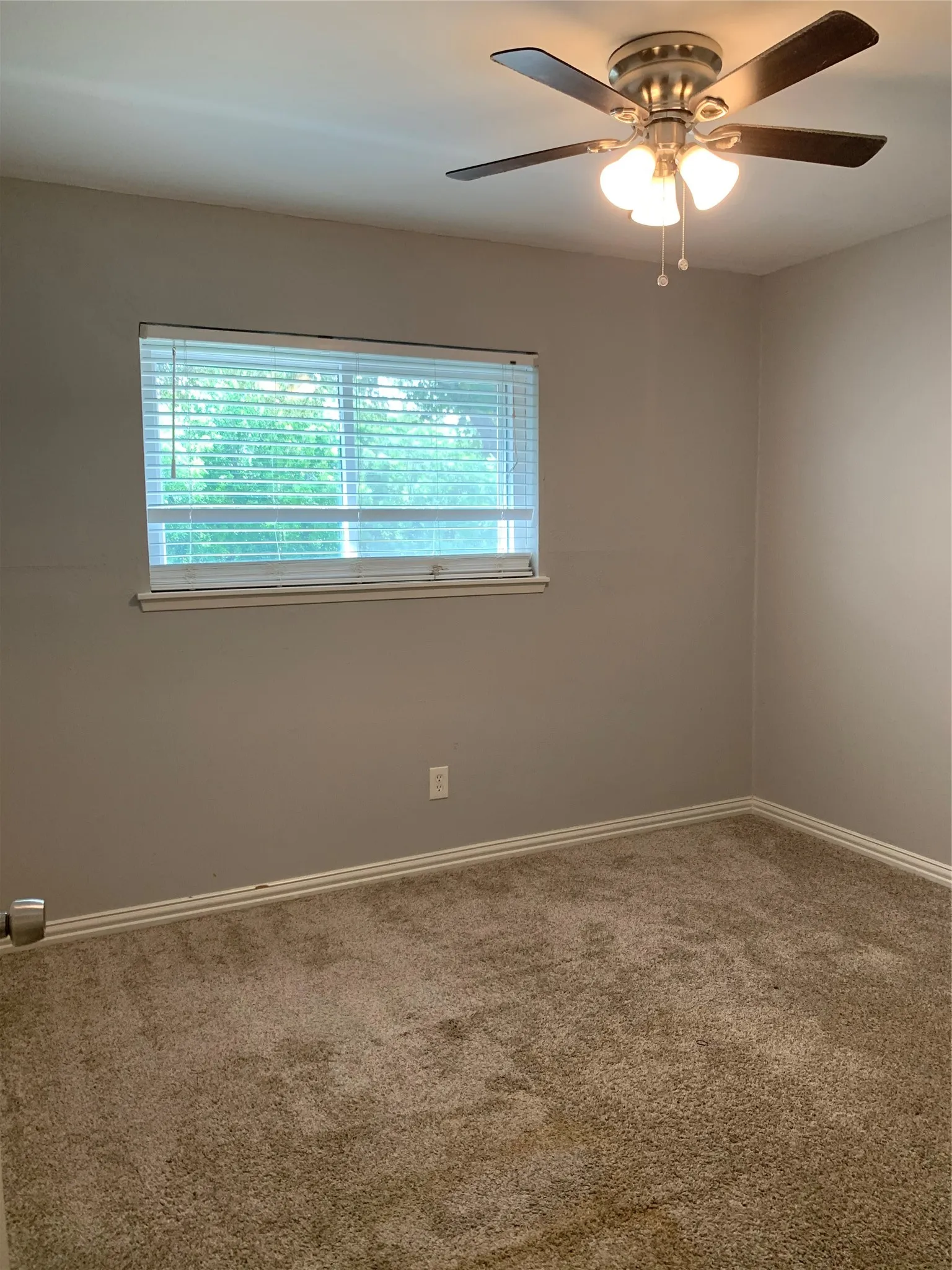 Bedroom featuring light tan walls, a ceiling fan with integrated lighting, a single window with blinds, and neutral-toned carpeting