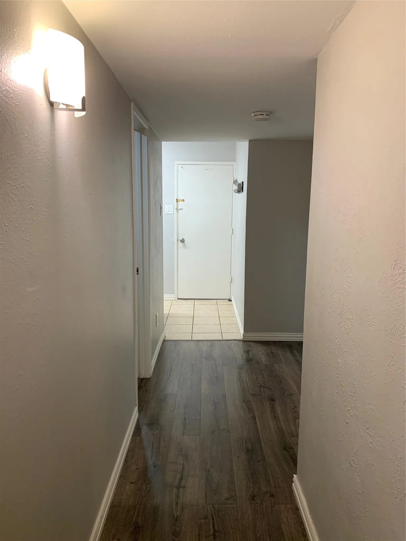 Hallway featuring wood-finish flooring, white baseboards, and neutral wall paint