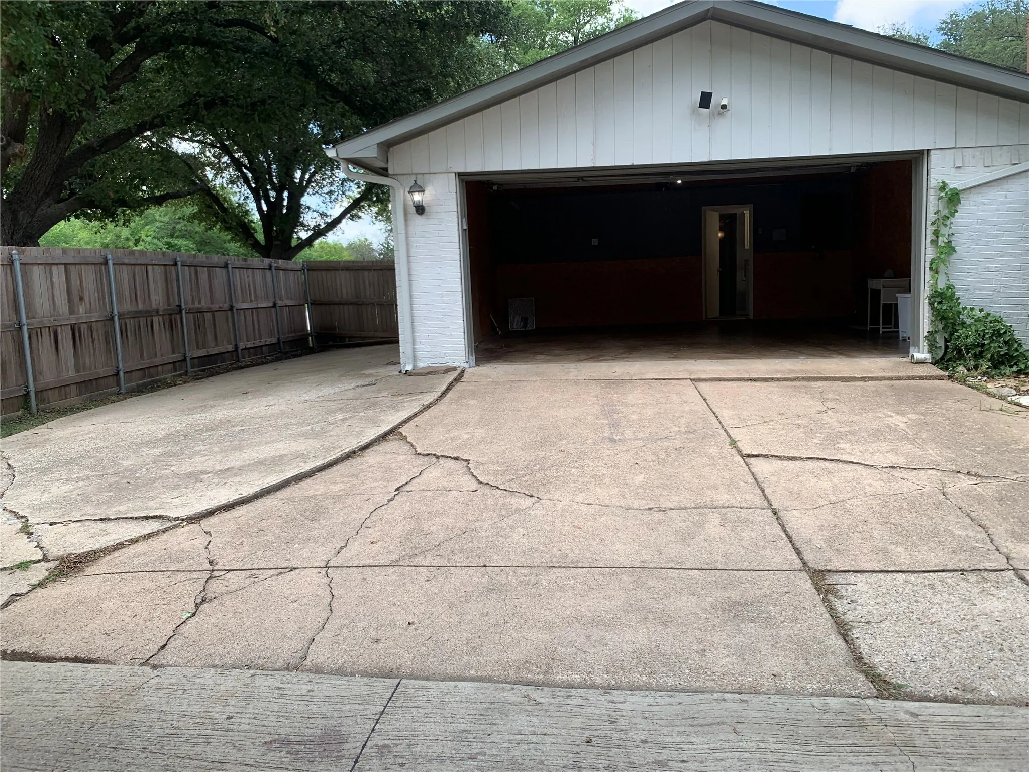 Attached open garage featuring a white painted brick exterior and wood panel siding