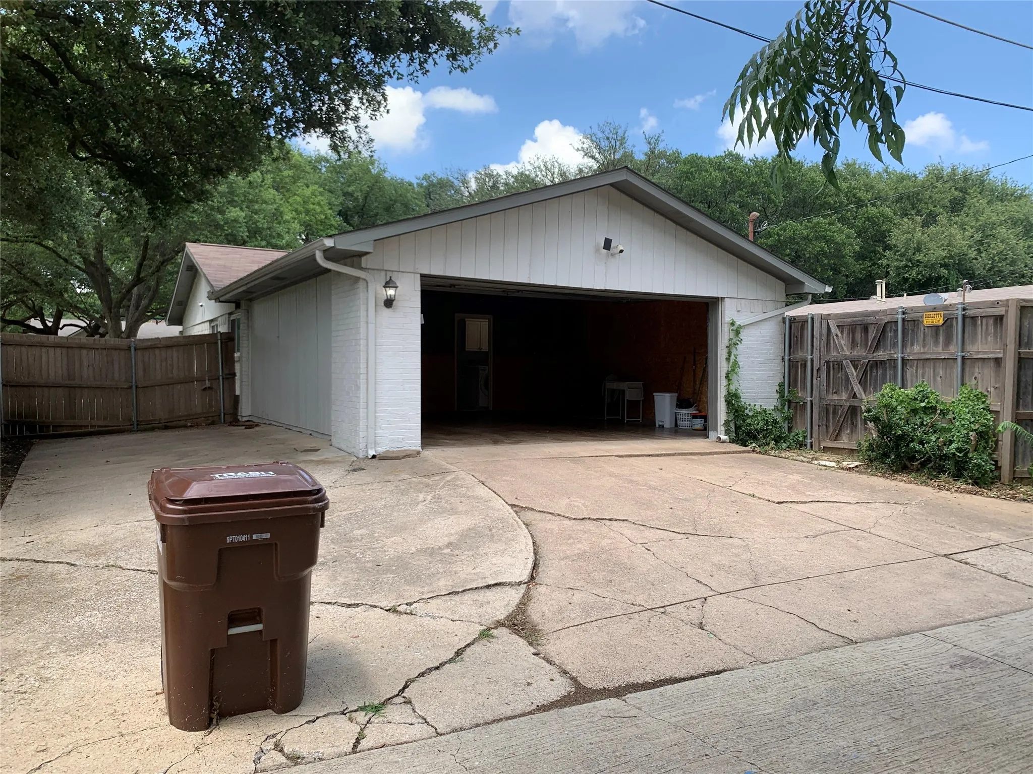 White painted brick exterior with a grey gable roof, featuring an attached garage with a drive-through bay