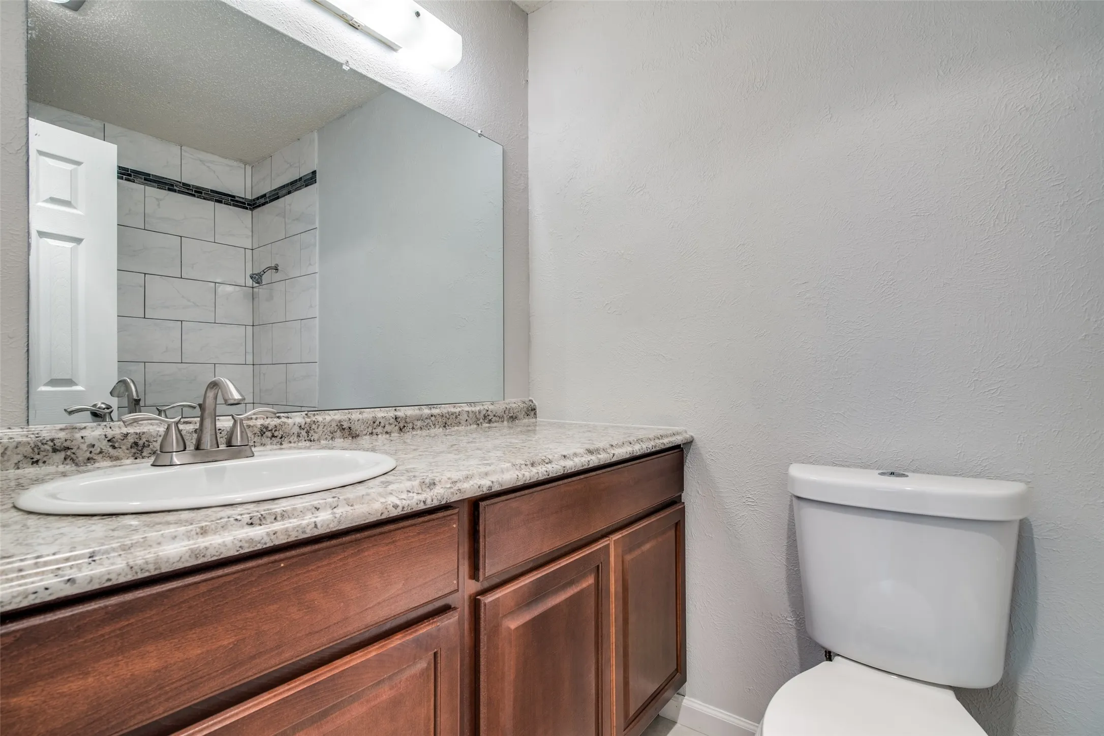 Bathroom vanity with a light-toned countertop, an undermount sink, and a brushed nickel faucet