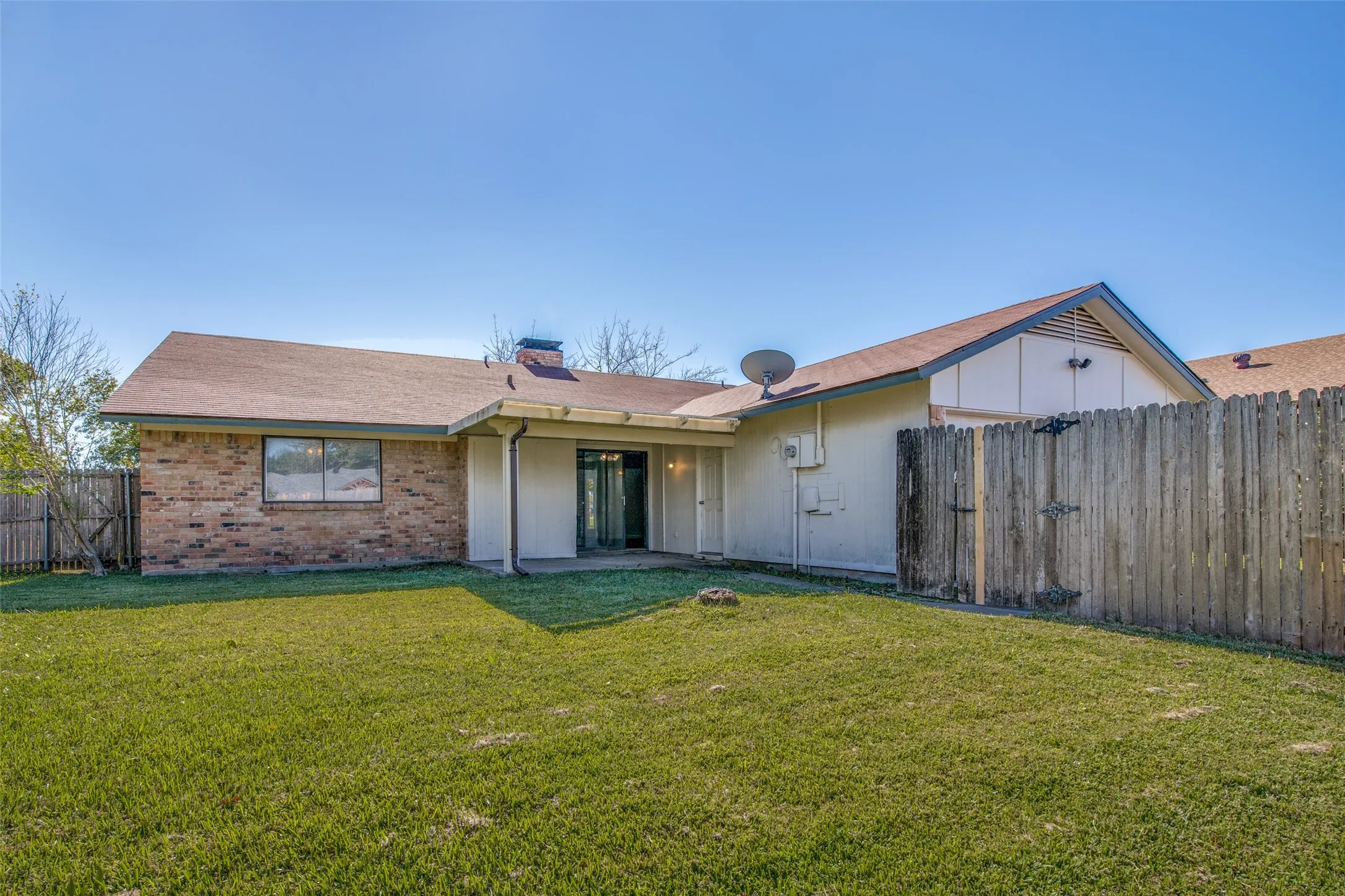 Expansive backyard featuring a manicured lawn, brick and siding exterior, and a privacy fence