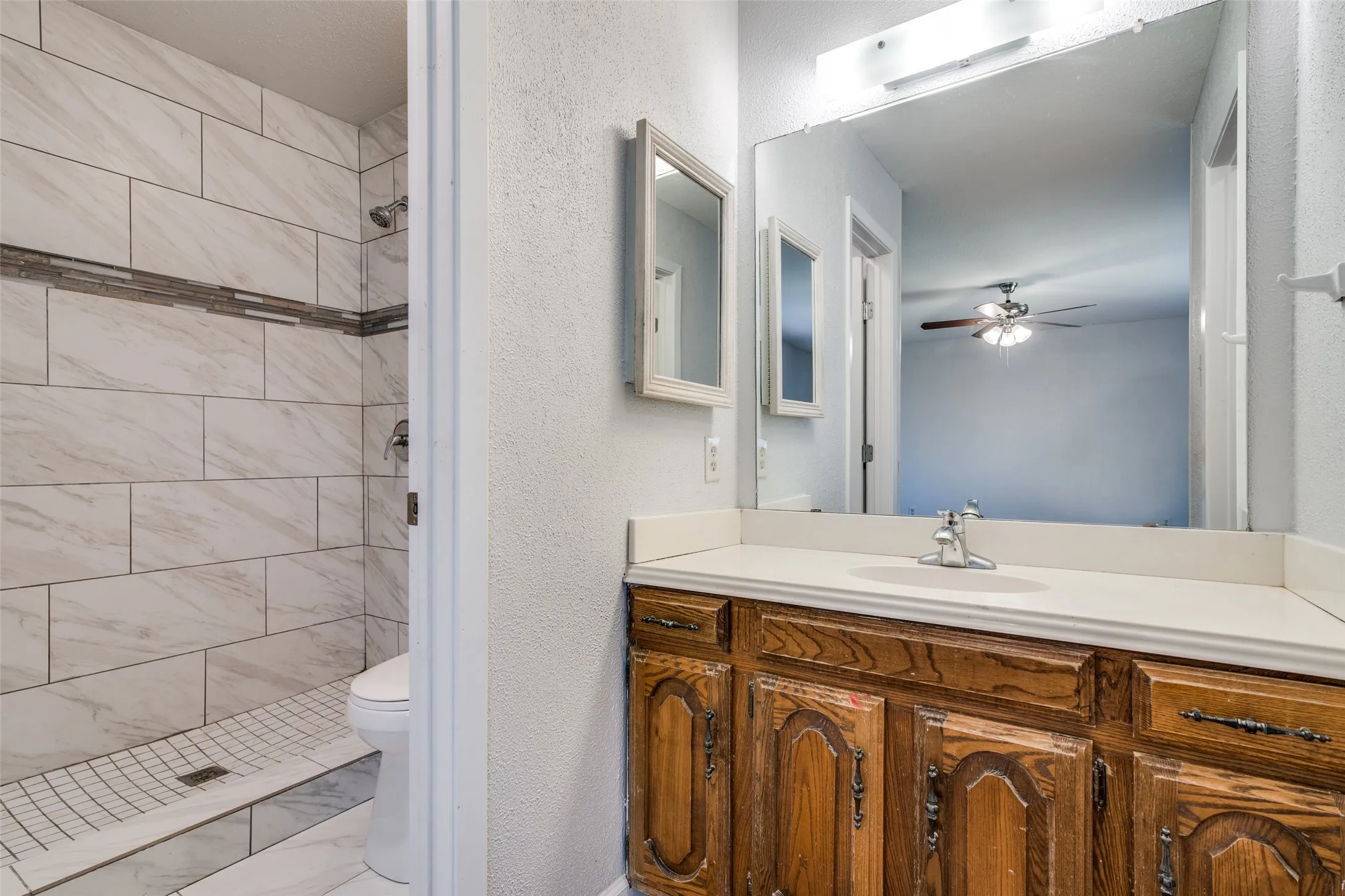 Walk-in shower with large format white tile and a decorative mosaic accent strip