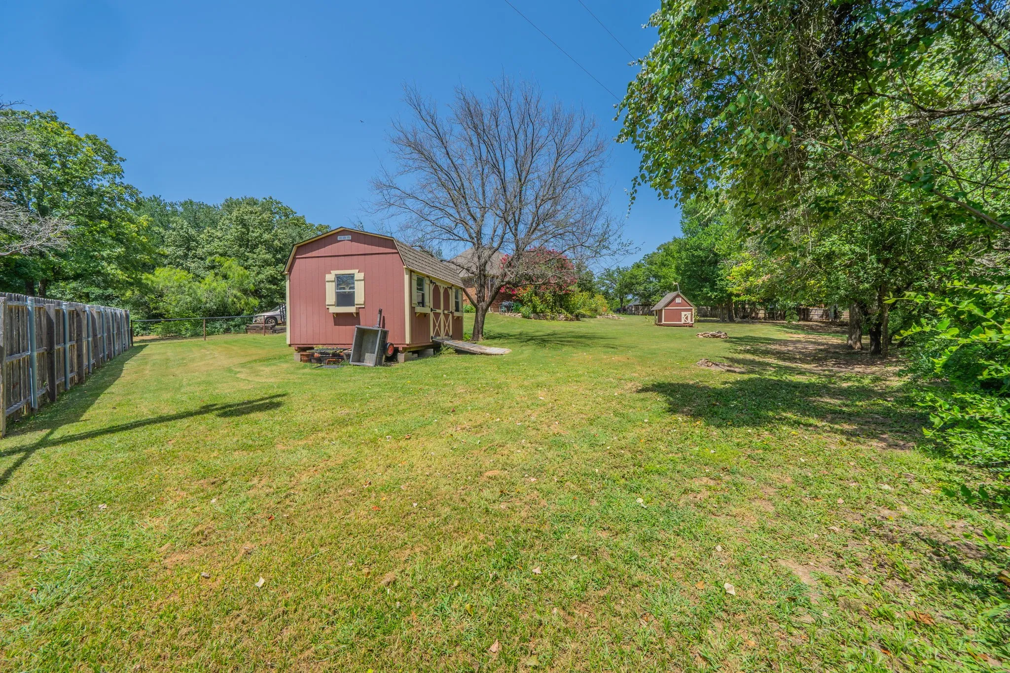 Back view of lot with storage building and play house.