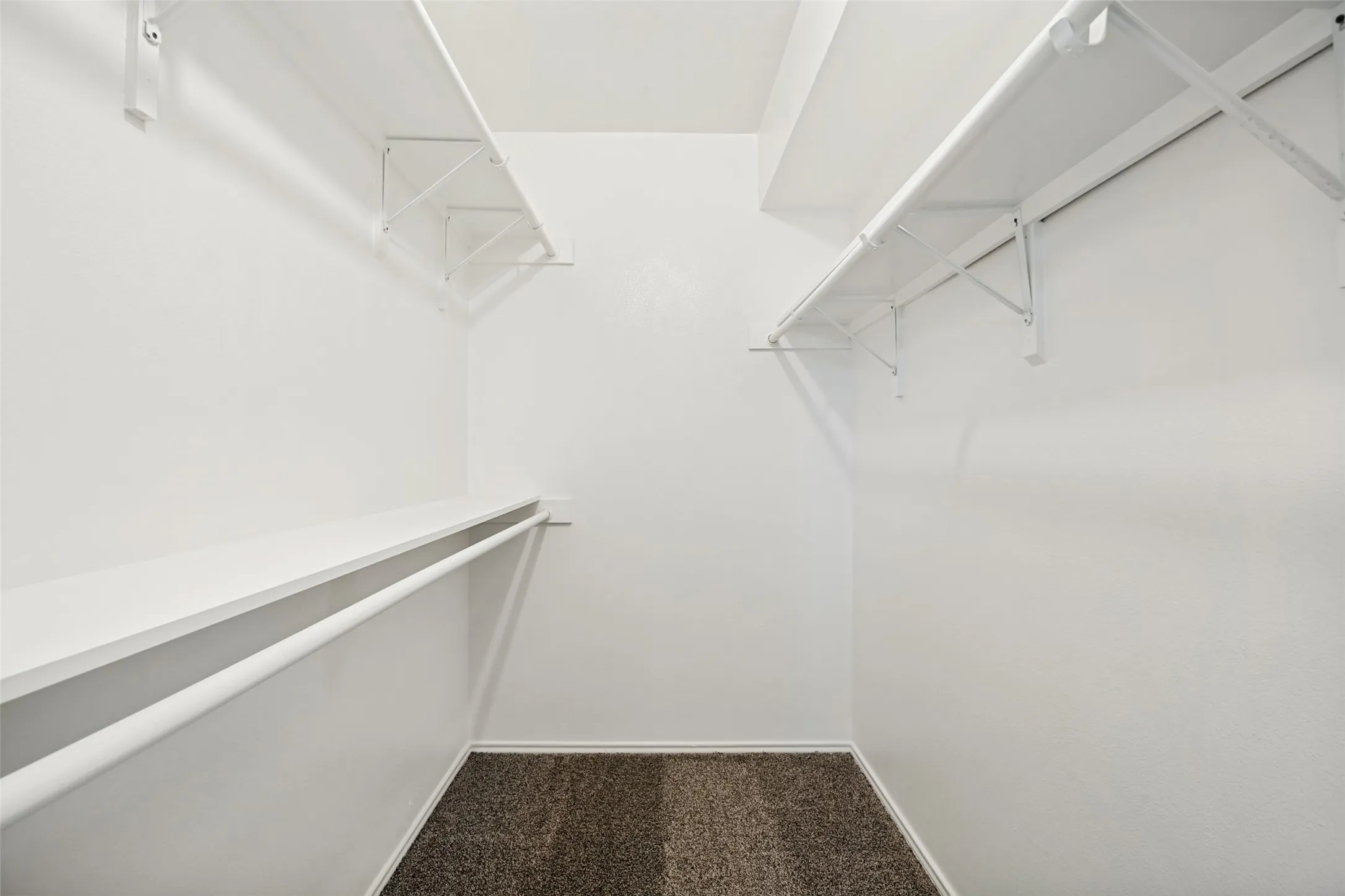 Walk-in closet featuring white wire shelving and hanging rods