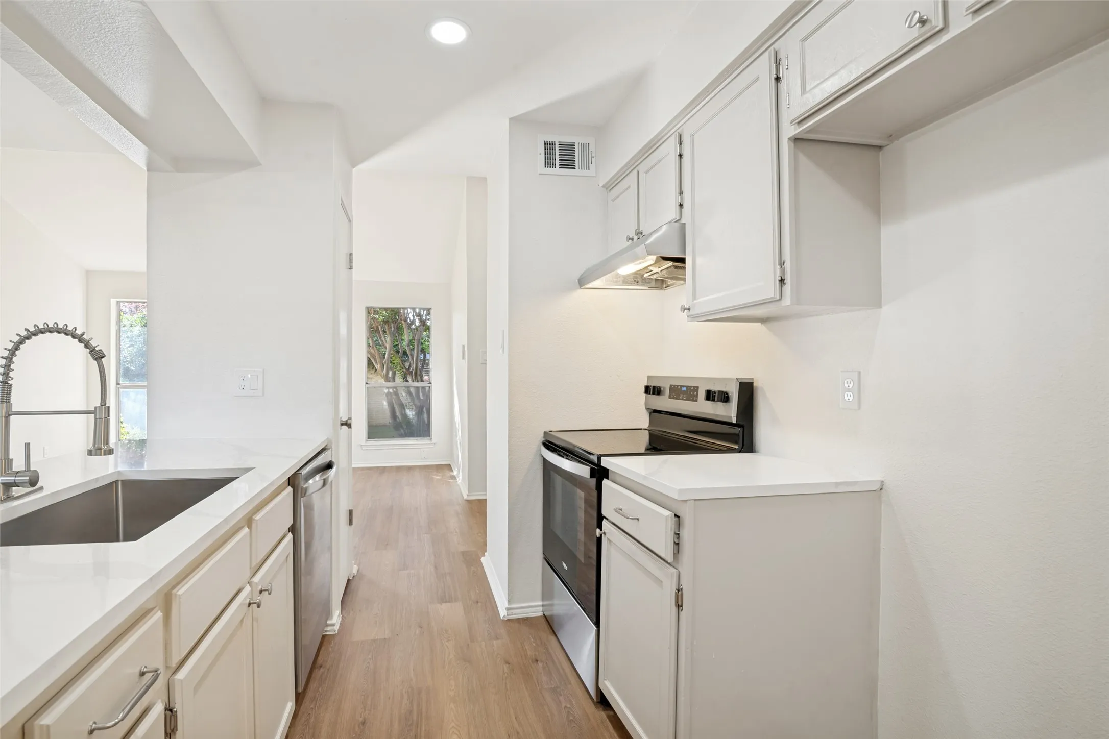 Contemporary kitchen featuring white cabinetry, light-toned countertops, and wood-finish flooring