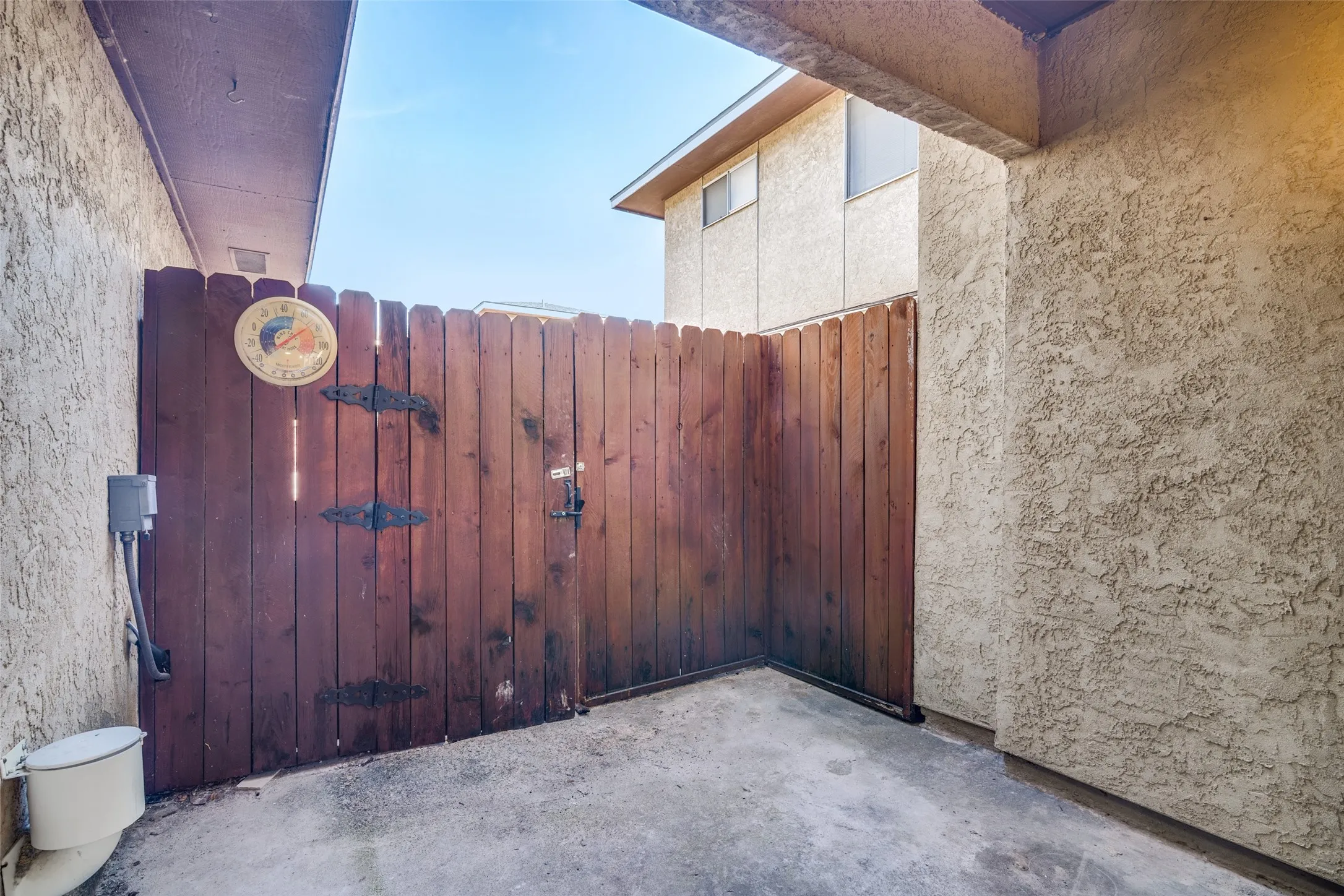 Private wood-paneled gate with black decorative hardware and concrete flooring