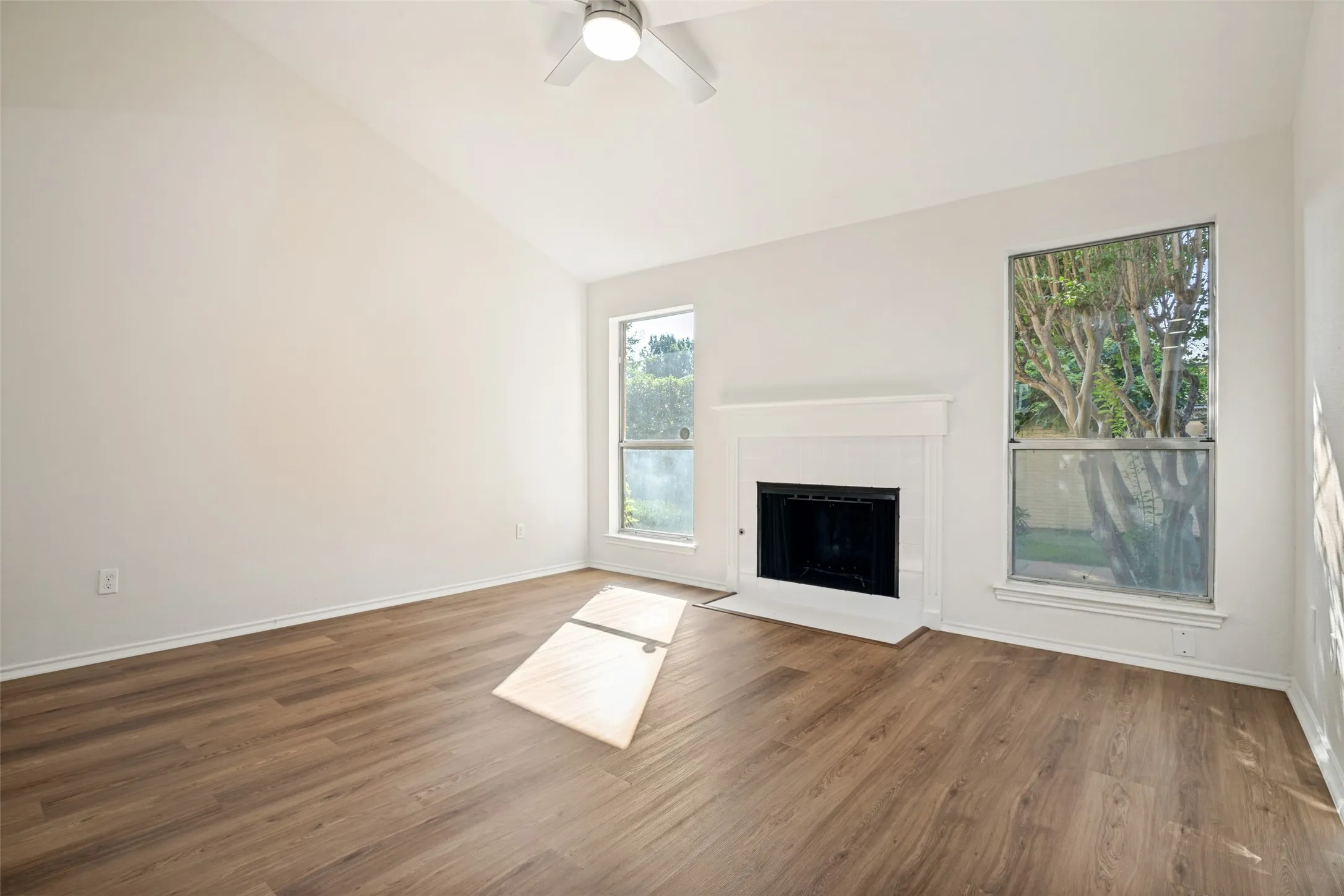 Bright interior space featuring a vaulted ceiling and wood-finish flooring