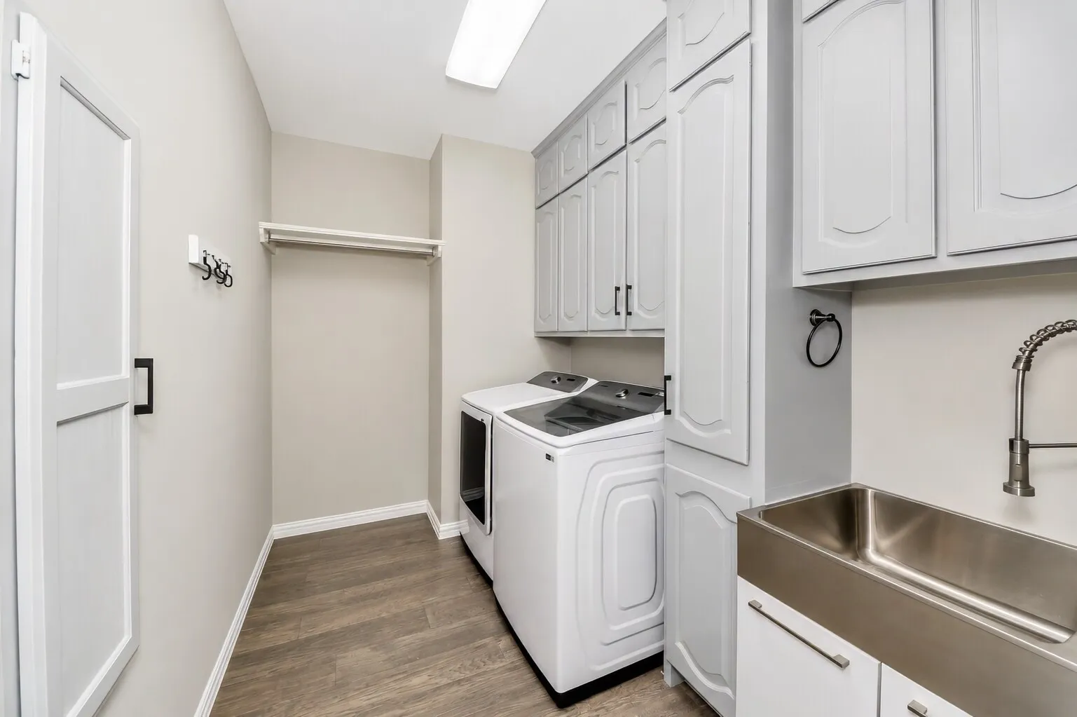The laundry room is designed for everyday efficiency, with a laundry chute tucked between the washer and the sink for quick drop-offs from upstairs. The layout has room for a full wine fridge if someone wants it, and the deep utility sink is ideal for bathing family pets or handling bigger cleanup tasks. It’s a bright, organized space that keeps the home running smoothly.