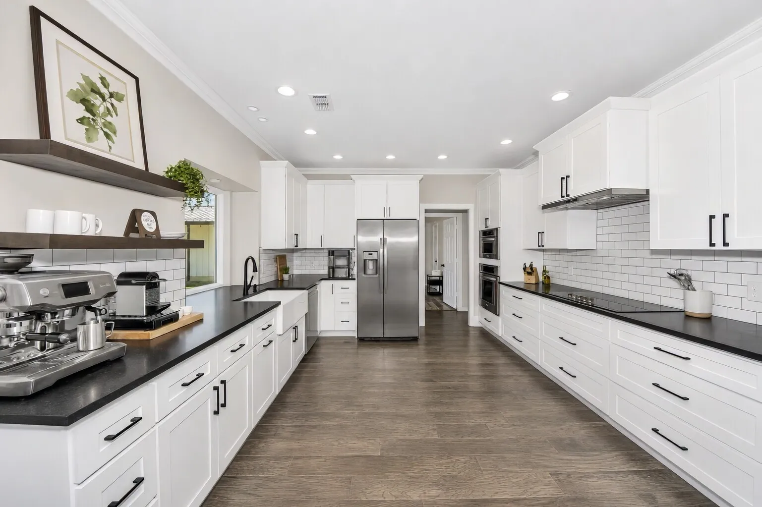 From the breakfast nook, you get a great look at the kitchen’s full prep zone — long stretches of counter space around the range, white cabinetry, and clean subway tile that make cooking feel easy and uncluttered. The coffee bar adds a warm everyday touch, while the stainless appliances keep the space feeling modern. This angle also shows how the kitchen connects naturally to the downstairs bedroom, giving the layout a smooth, practical flow that works beautifully for guests, multigenerational living, or a quiet retreat tucked just off the main living areas.