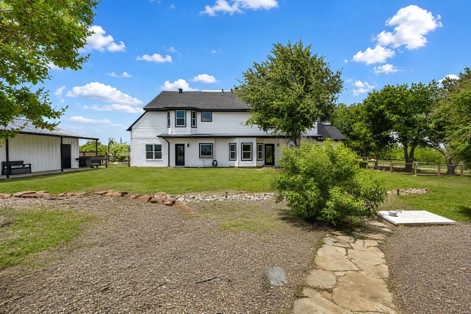 The backyard offers a wide, open view of the property with mature trees and plenty of space to enjoy. To the right of the bush, the storm shelter is easily accessible, with stairs leading down to the lower level for peace of mind during severe weather. The large shed to the left adds valuable storage and flexibility for tools, hobbies, or outdoor equipment. It’s a practical, well-laid-out outdoor space that fits everyday living as well as weekend projects.