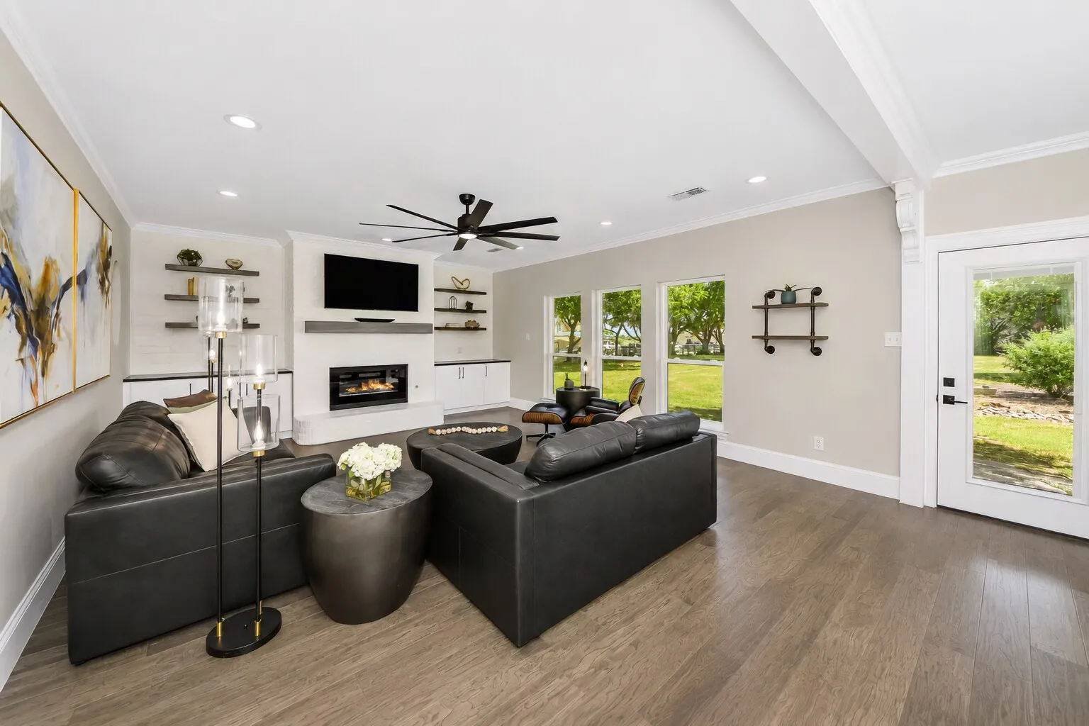 The living room sits at the back of the home with wide windows that open to beautiful backyard views and natural light. The electric fireplace adds an easy, modern touch, and the space is already plumbed for gas if someone prefers it. Deep built-ins offer plenty of storage for games, media, or décor, keeping the room streamlined and comfortable. It’s a bright, relaxed gathering space designed for everyday living.
