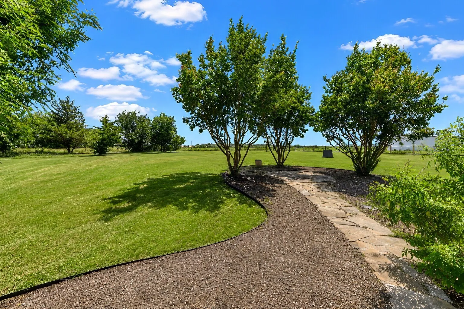 The pathway leading to the crepe myrtles offers a shaded, peaceful spot perfect for unwinding at the end of the day. It’s an easy place to slow down — sip iced tea, read a book, or simply enjoy the breeze under the trees. With the natural canopy and open lawn around it, this area makes an ideal setting for a hammock and quiet evening relaxation.