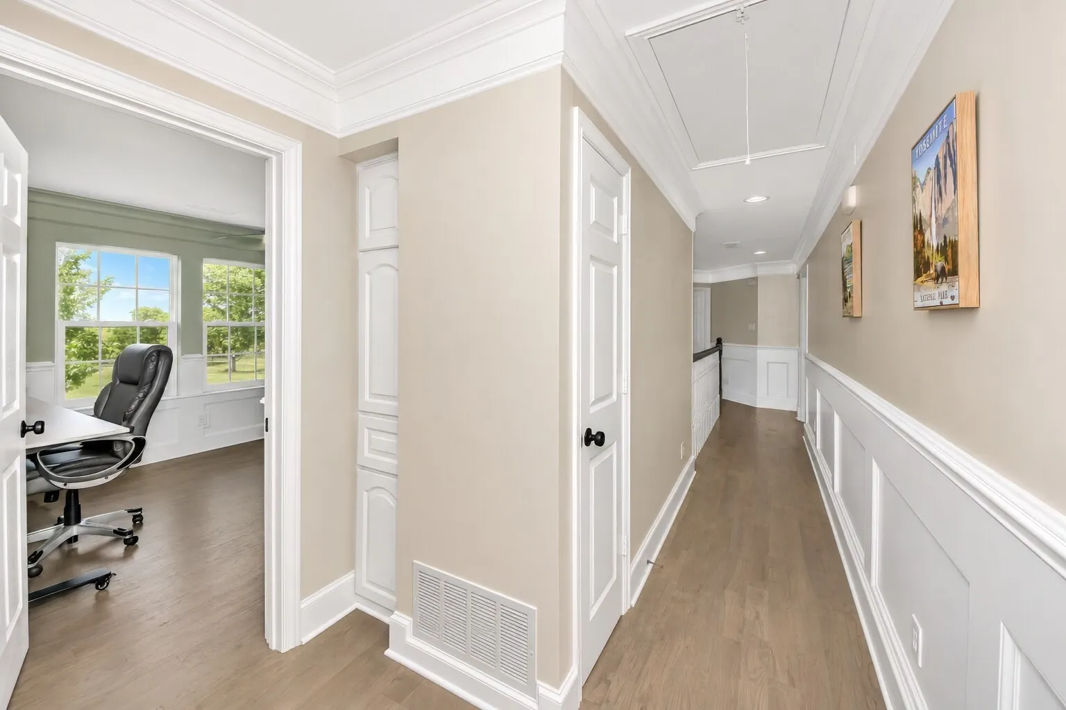 Standing just outside the primary bedroom, the hallway offers a clean, bright transition to the rest of the upstairs. A built-in lower cabinet on the left hides a convenient laundry chute that leads directly into the laundry room downstairs. The room to the left can serve as an office or an additional bedroom, giving the layout flexibility for work, guests, or hobbies. It’s a thoughtful, easy-to-use space that keeps everyday living simple and connected.