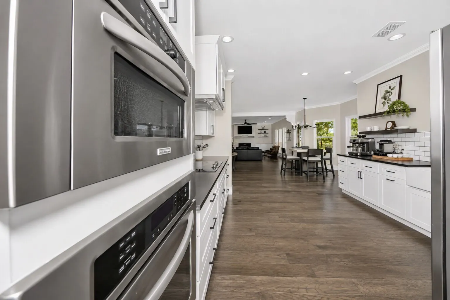 This angle shows the heart of the home — a clean, modern farmhouse kitchen that opens effortlessly into the dining nook and living room. Stainless appliances, quartz counters, and subway tile keep the kitchen feeling fresh, while the open layout makes everyday living easy. From morning coffee at the nook to movie nights in the living room, the space feels connected, bright, and designed for how people actually live today.