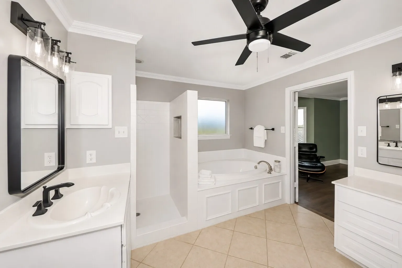 The primary bathroom offers both a jetted tub and a separate walk-in shower, giving you options for winding down or starting the day. Soft lighting, framed mirrors, and black accents keep the space feeling fresh and modern, while the layout stays open and easy to use. It’s a bright, comfortable room designed for everyday convenience with a touch of spa-like calm.