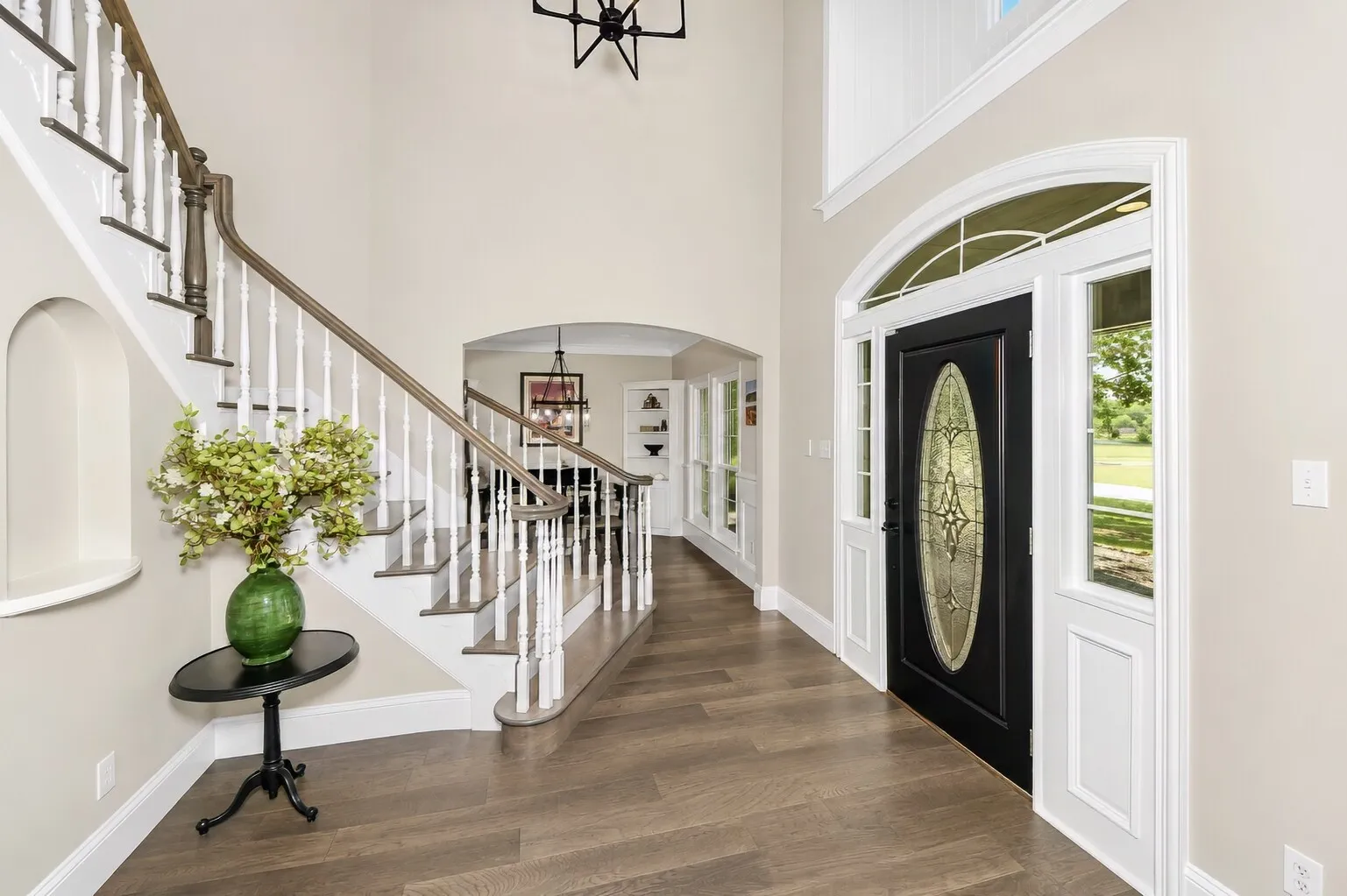 From the dining room, the foyer opens to a curved staircase that becomes the main architectural moment of the entry. The lines stay clean and bright, with natural light carrying through to the back of the house where the den sits. It’s a simple, welcoming transition that shows off the flow of the home without giving away the full den setup just yet.