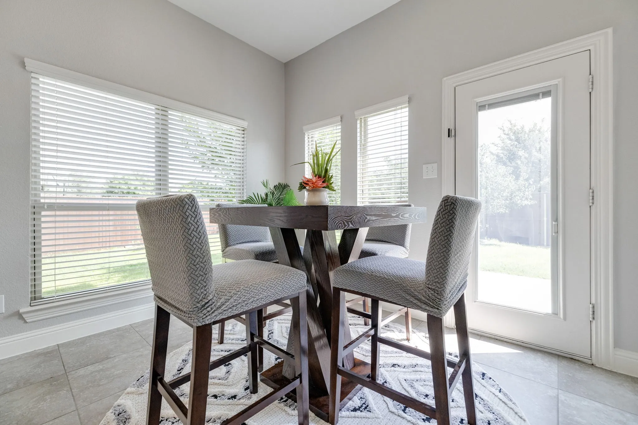 Dining area featuring large windows with blinds, a glass-paneled exterior door, and tile flooring