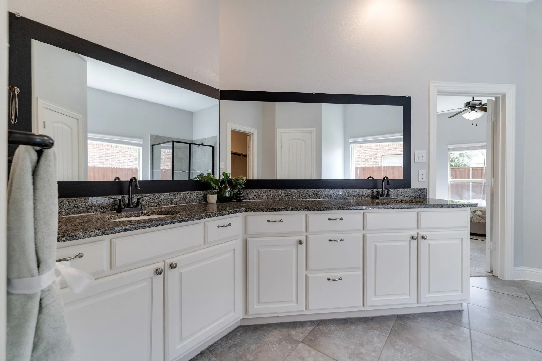 Dual vanity featuring granite countertops, undermount sinks with matte black fixtures, and extensive white cabinetry