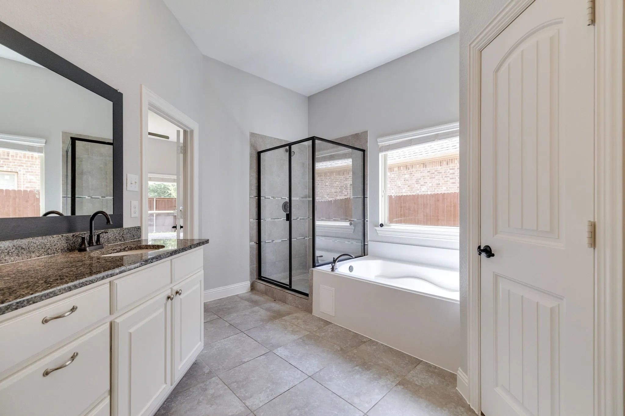 Bright bathroom featuring a single vanity with stone countertop, undermount sink, and matte black faucet