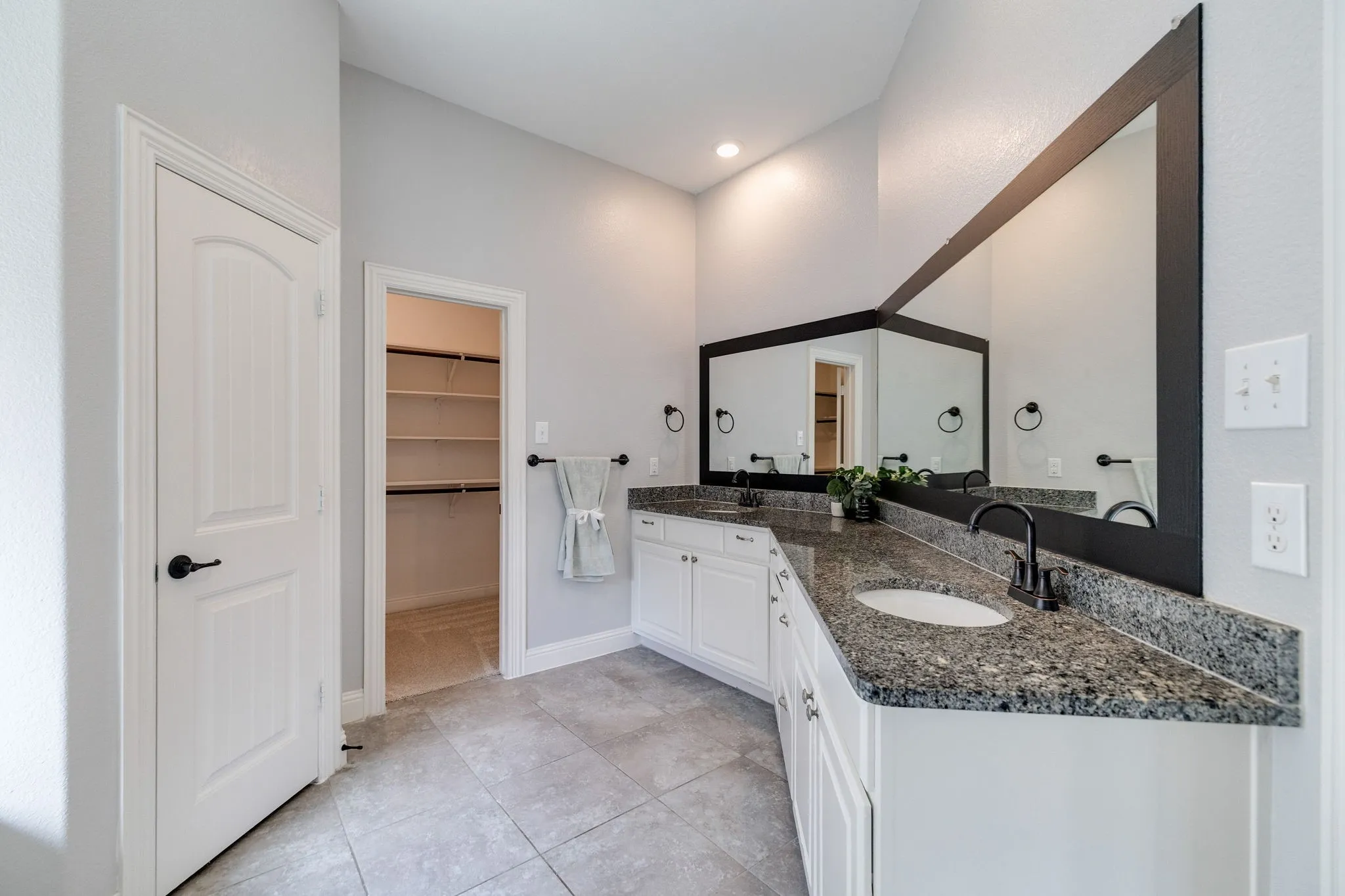 Bathroom featuring a double vanity with granite countertops, white cabinetry, and matte black fixtures