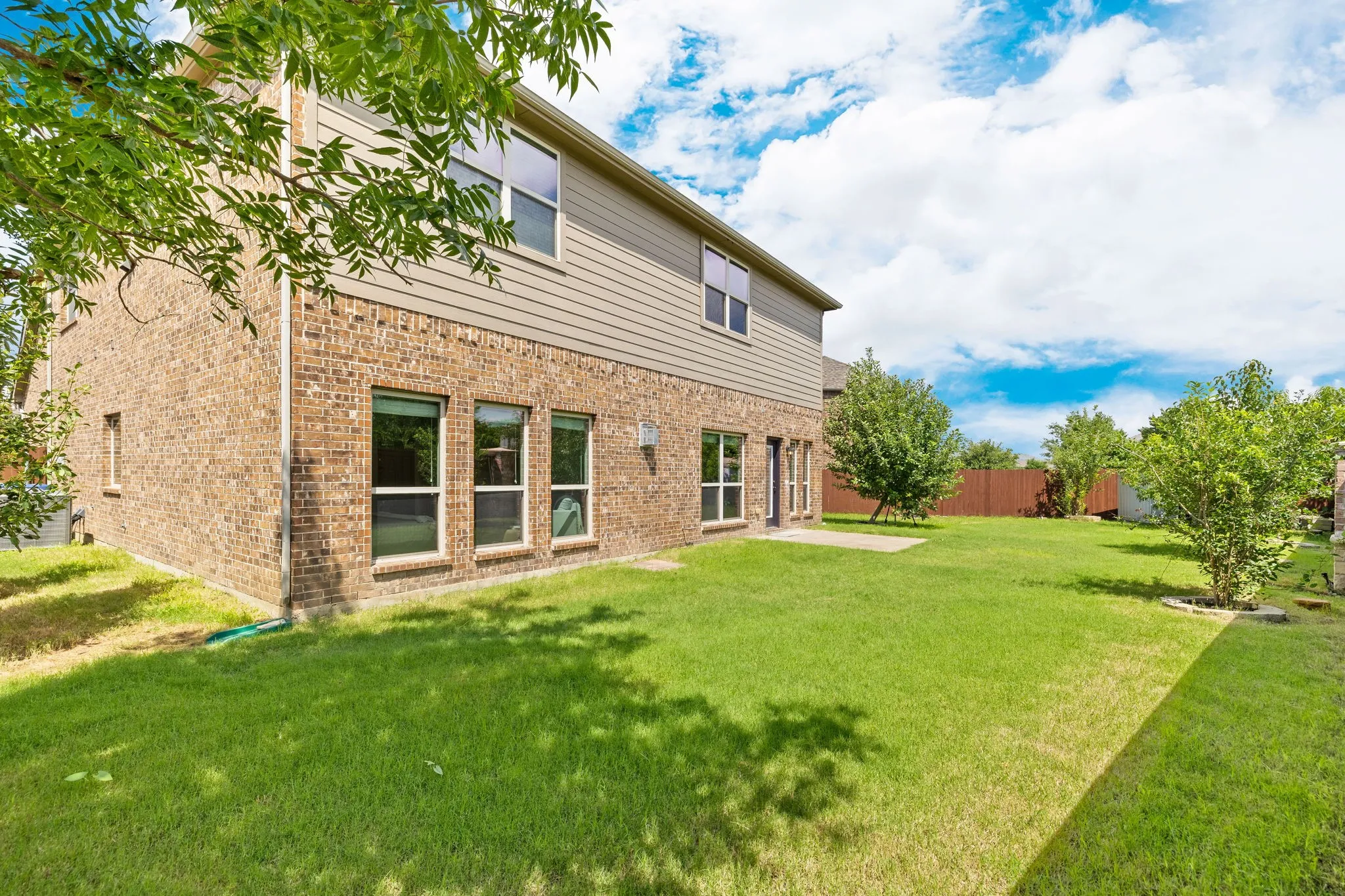 Expansive rear yard featuring a verdant lawn, mature plantings, and a privacy fence