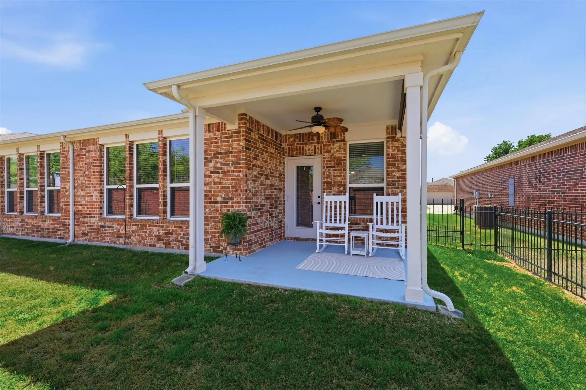Covered back patio with ceiling fan, perfect for relaxing or enjoying the spacious backyard.