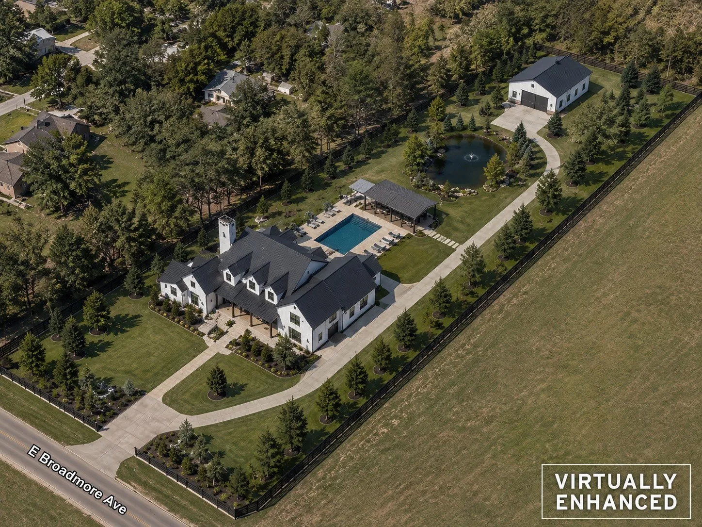 Unimproved property - This is an example only - White exterior residence with a dark roof, extensive paved driveway, detached ancillary building, a swimming pool, and a pond with a fountain - virtually staged