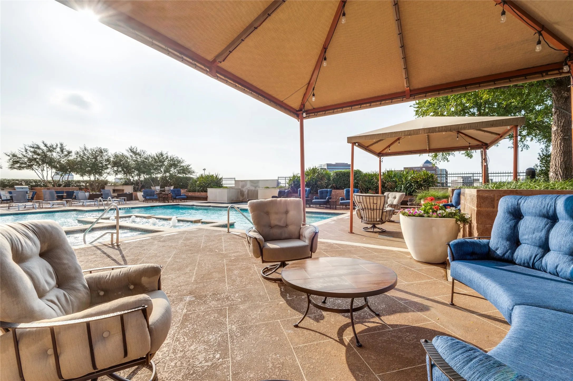 Expansive outdoor lounge area featuring a large swimming pool with integrated spa, a shaded pergola, and a separate cabana structure