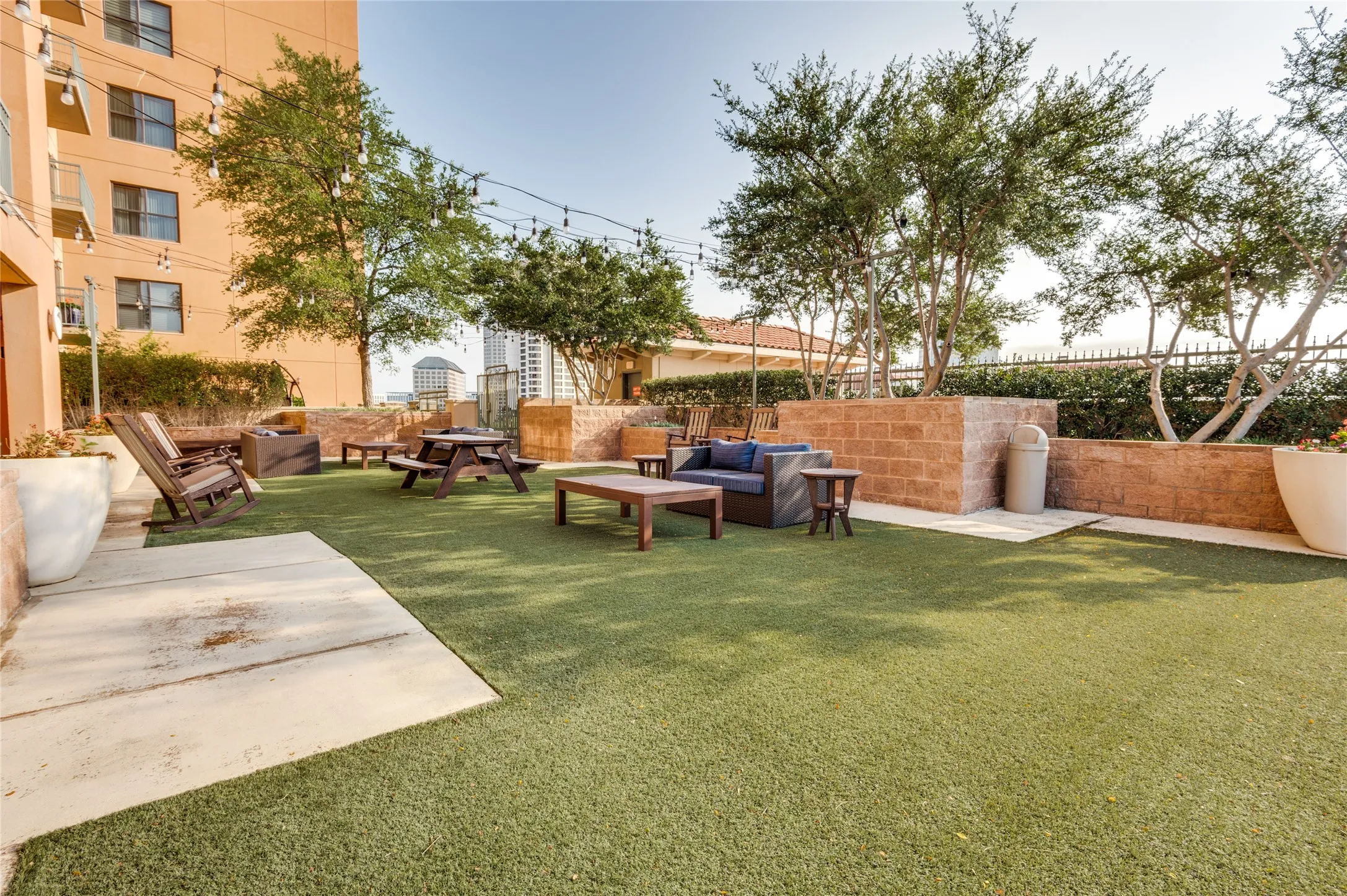 Landscaped outdoor area featuring artificial turf, string lighting, and mature trees